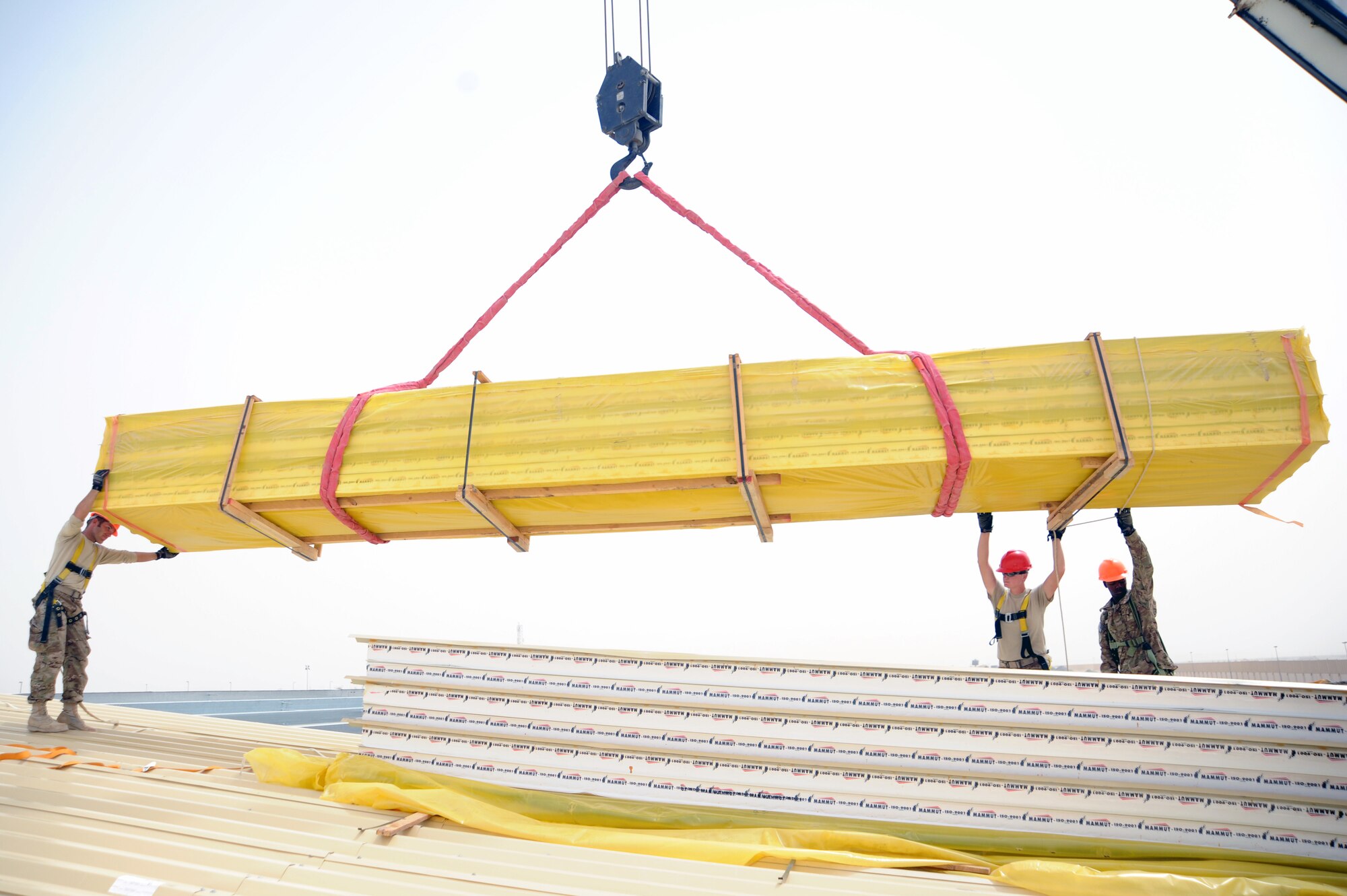 SOUTHWEST ASIA  - Members of the 557th Expeditionary RED HORSE Squadron guide insulated roof panels onto a construction site March 22, 2012. Roughly 30 Rapid Engineer Deployable Heavy Operations Repair Squadron Engineers are deployed to assist the 380th Air Expeditionary Wing by constructing three, 20,000 square-foot warehouses to store items sensitive to the harsh weather conditions in the area. (U.S. Air Force photo/1st Lt. Victoria Porto)
