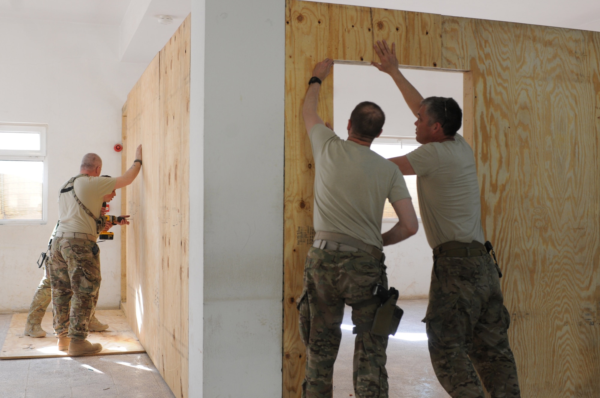 NATO advisers with the 438th Air Expeditionary Wing’s Thunder Lab immersion training center, sheet the walls during the building of a classroom at Shindand Air Base, Afghanistan, March 21, 2012. The advisers helped build classrooms, a multipurpose room and an aviation simulator room that will be used as Shindand’s English language training center (SELTC) for the Afghan air force Thunder Lab pilot candidates. (U.S. Air Force photo by Staff Sgt. Nadine Y. Barclay)