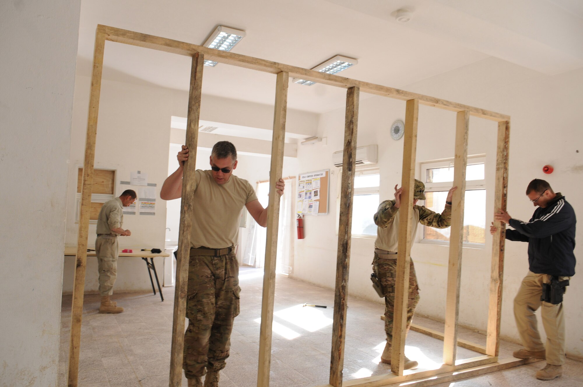 NATO advisers with the 438th Air Expeditionary Wing’s Thunder Lab immersion training center raise the frame of a wall during the building of a classroom at Shindand Air Base, Afghanistan, March 18, 2012. The advisers helped build classrooms, a multipurpose room and an aviation simulator room that will be used as Shindand’s English language training center (SELTC) for the Afghan air force Thunder Lab pilot candidates. (U.S. Air Force photo by Staff Sgt. Nadine Y. Barclay)