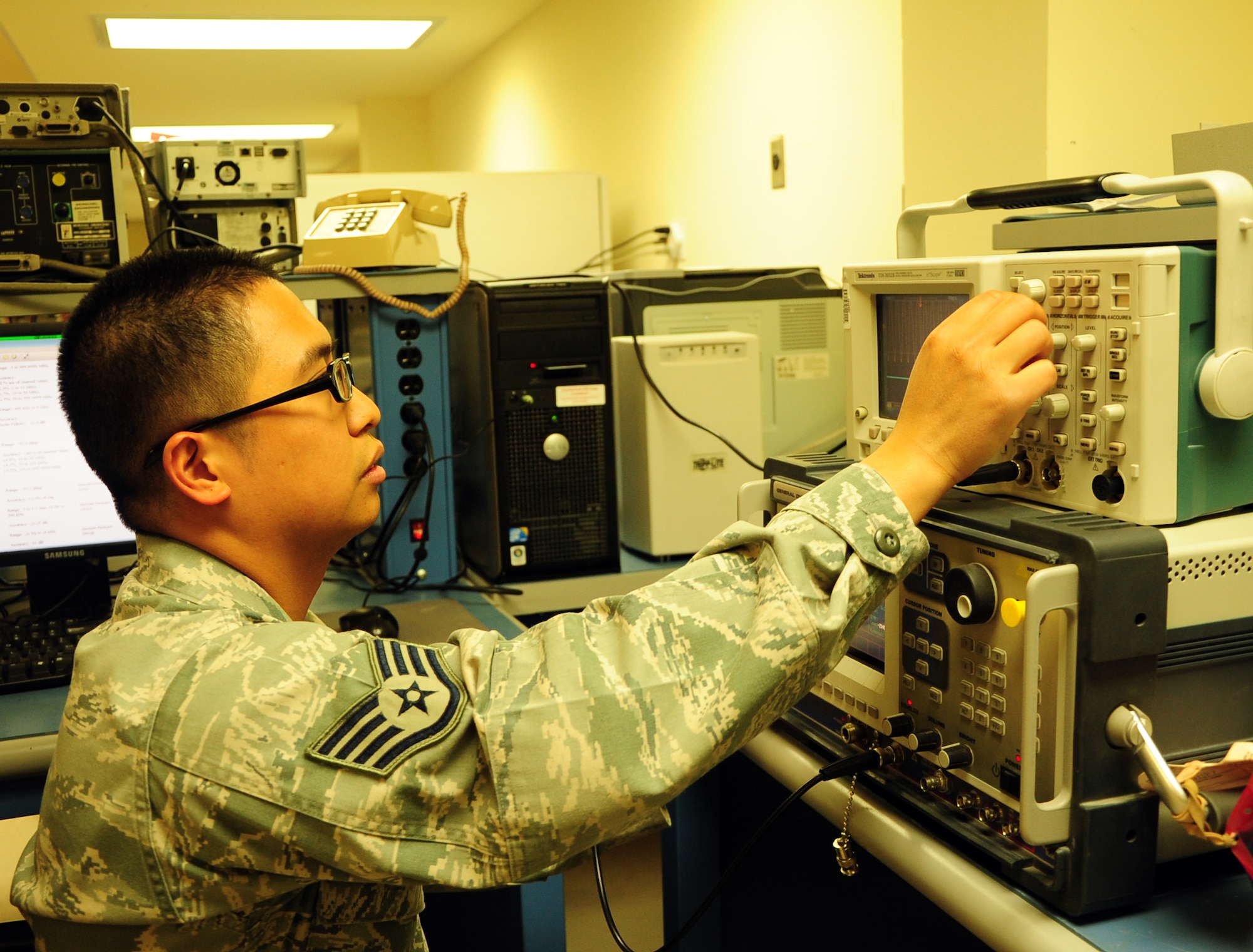 Staff Sgt. Emil Gomez, a Precision Measurement Equipment Laboratory technician and native of Kapolei, Hawaii, uses a frequency calibrator at the 379th Expeditionary Maintenance Squadron PMEL shop here March 13. The frequency calibrator tests different panels and electrical equipment to ensure they can properly detect certain radio waves.  PMEL is responsible for the proper calibration of more than 16,000 items ranging from screws to radar systems. Gomez is currently deployed from Yakota Air Base, Japan. (U.S. Air Force photo/ Senior Airman Michael Charles)