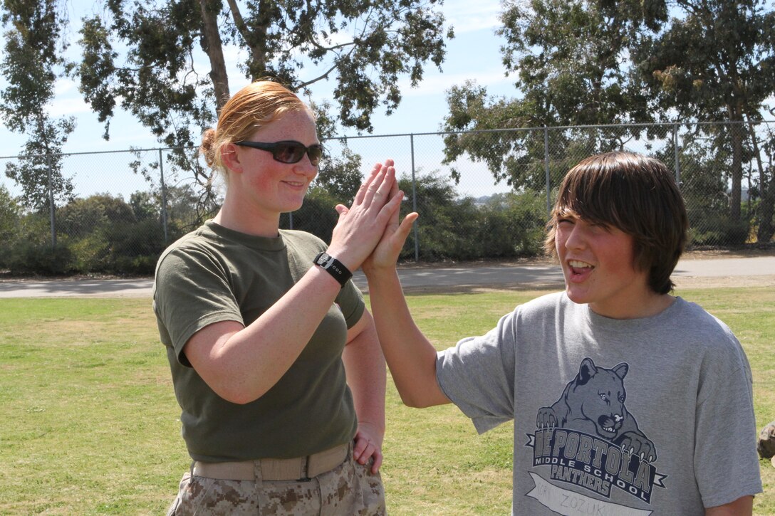 Pfc. Joyce Kaminski, a motor transportation mechanic with Marine Wing Communications Squadron 38 and a Longview, Wash., native, gives a student a high five during a physical education fitness challenge with De Portola Middle School, March 23. Approximately 40 Marines from Marine Corps Air Station Miramar, Calif., came to support the event, guiding nearly 1,000 students through the various exercises for the challenge.