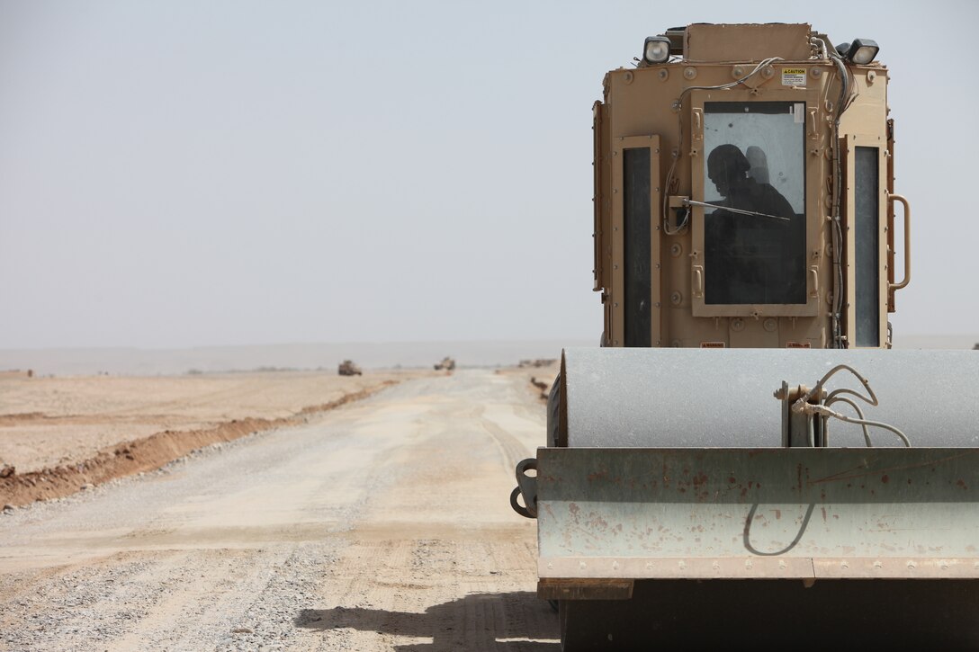 Using a compactor, a heavy equipment operator with Support Company, 9th Engineer Support Battalion, 1st Marine Logistics Group (Forward) creates a hardball road outside of Forward Operating Base Geronimo, March 23. Marines lay down gravel, add water and compact the road. The process creates a smooth surface similar to roads in America.