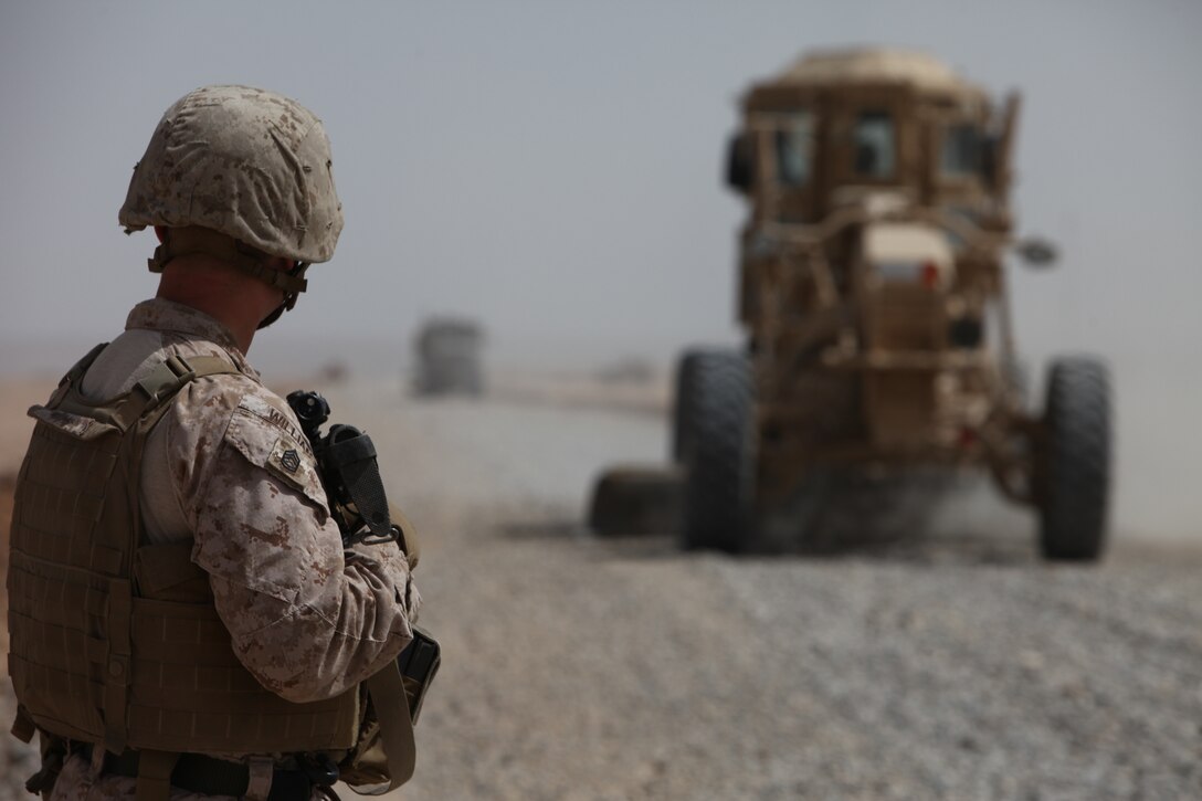 Gunnery Sgt. Joel Williams, heavy equipment chief, Heavy Equipment Platoon, Support Company, 9th Engineer Support Battalion, 1st Marine Logistics Group (Forward) watches while a grader levels the gravel during road construction outside of Forward Operating Base Geronimo, March 23.