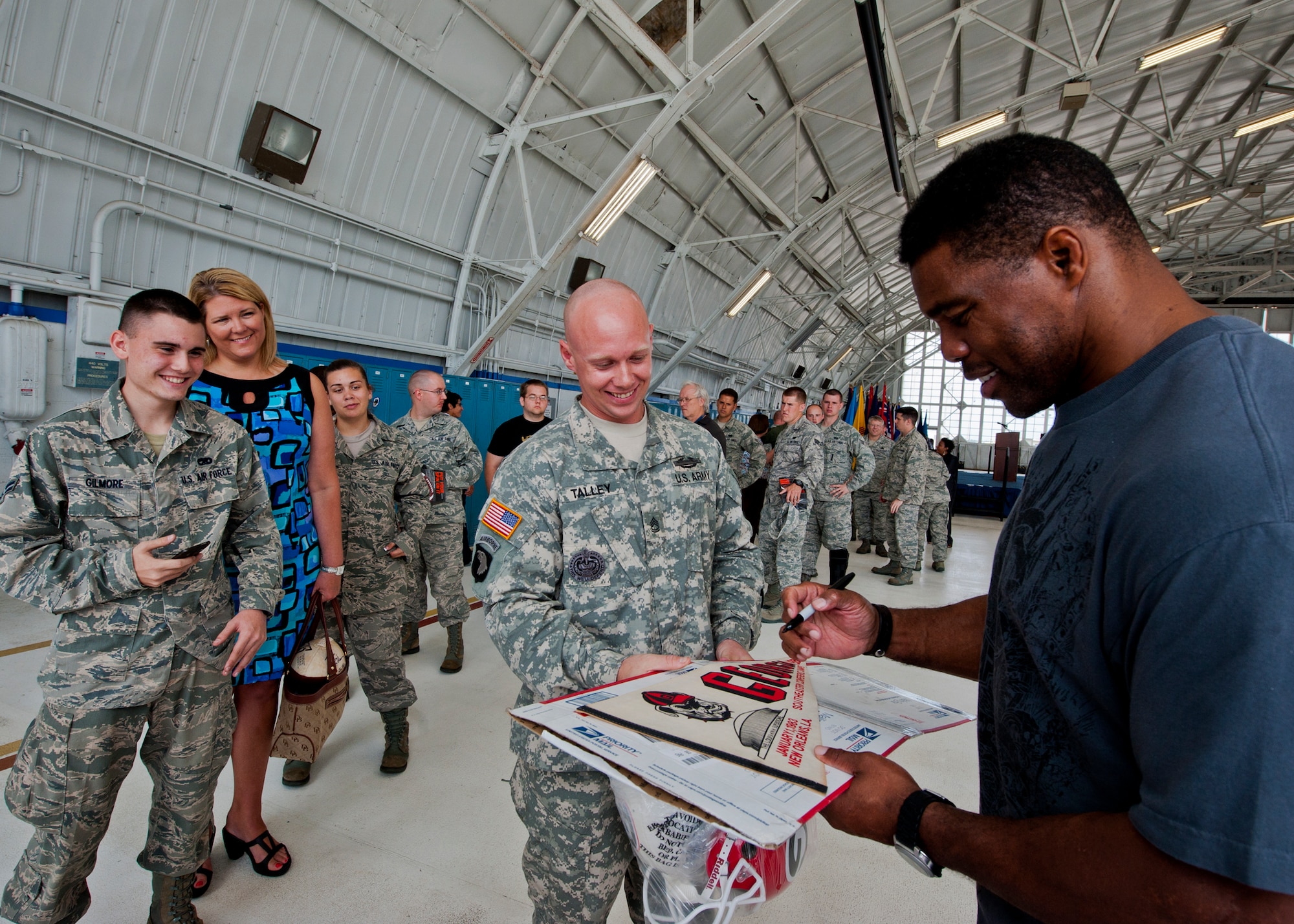 Sgt. 1st Class Matthew Talley, of the 719th Contingency Contracting Team, gets Herschel Walker to sign his 1983 Georgia Bulldogs pennant March 22 at Eglin Air Force Base, Fla.  Walker visited the base to speak about resiliency and the importance of asking for help. He spoke twice to large crowds of Team Eglin members about his life, career and the emotional and mental struggles he encountered throughout.  (U.S. Air Force photo/Samuel King Jr.)