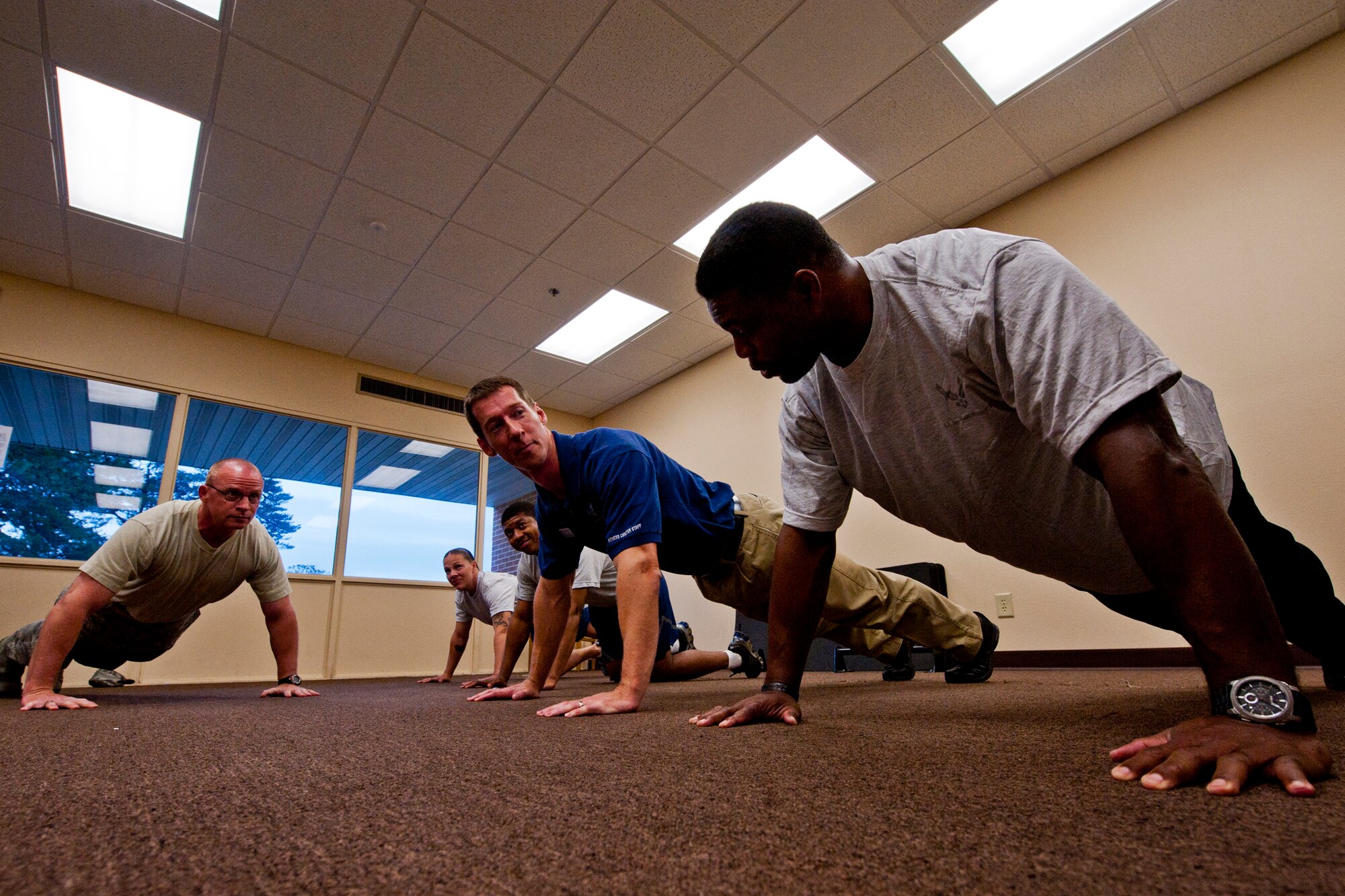 Chief Master Sgt. Brian Randolph, 46th Test Wing command chief, and Ben Gleason, a 96th Air Base Wing fitness program liaison, prepare to do pushups with Herschel Walker March 22 at Eglin Air Force Base, Fla.  Walker spoke with Airmen prior to their physical training test about his own no-weights workout routine of more than 1,500 pushups a day.  He also spoke twice to large crowds of Team Eglin members about his life, career and the emotional and mental struggles he encountered throughout.  His message was about resiliency and the importance of asking for help. (U.S. Air Force photo/Samuel King Jr.)