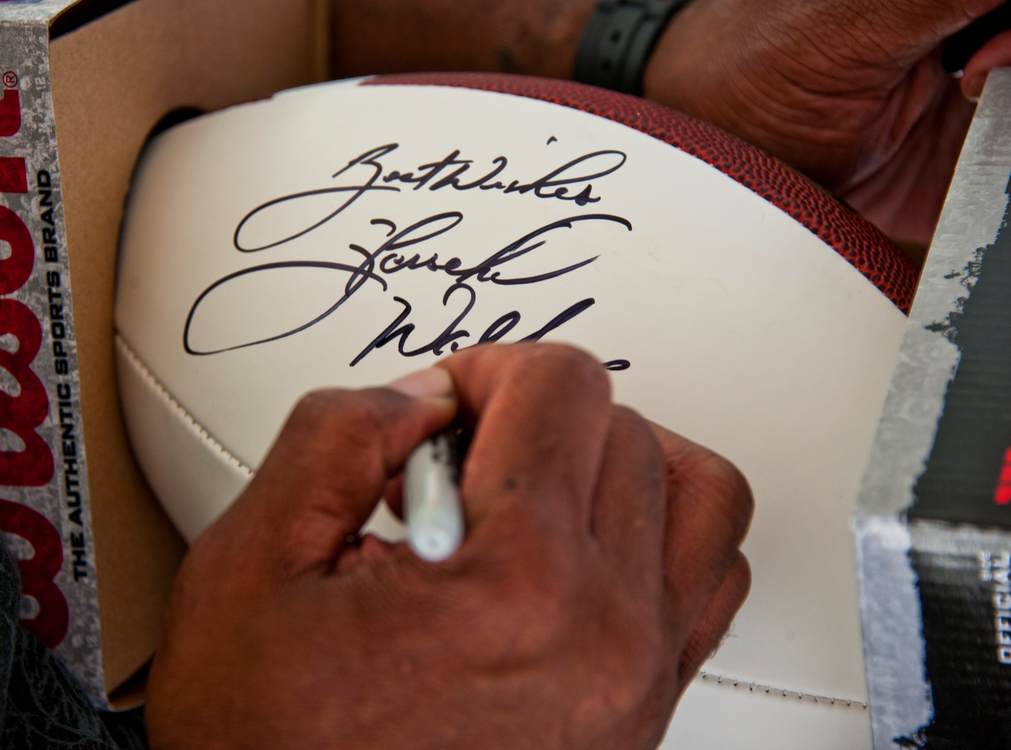 Herschel Walker signs a football for a fan March 22 at Eglin Air Force Base, Fla.  Walker visited the base to speak about resiliency and the importance of asking for help. He spoke twice to large crowds of Team Eglin members about his life, career and the emotional and mental struggles he encountered throughout.  (U.S. Air Force photo/Samuel King Jr.)