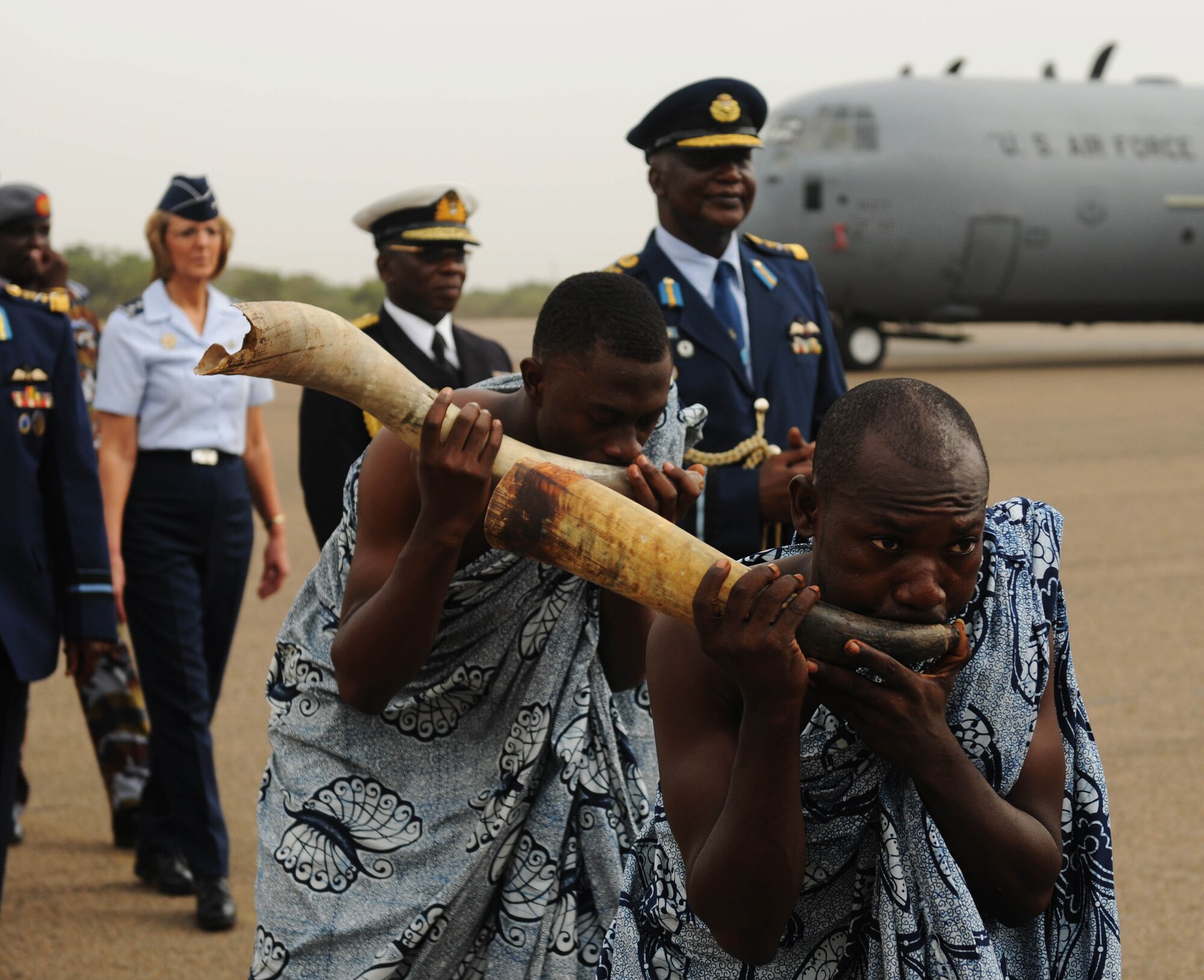 ACCRA, Ghana -- Ghanaian locals, right, play traditional Ghanaian instruments as they  lead the African Partnership Flight 12-2 official party down the flightline during the APF 12-2 closing ceremony March 23 here. APF 12-2 is military-to-military partnership building exercise that gave Ghanaian, Togolese, Senegalese, Nigerian, Benin and U.S. Air Force the opportunity to share ideas, techniques and practices to strengthen each nations air-security. During the two-week exercise the six partnering nation's shared experience in various fields to include: medical, search and rescue, aircraft marshalling, aircraft loading, security, safety, public affairs, aircraft maintenance and chaplain services. (U.S. Air Force photo by Senior Airman Natasha Stannard/Released)