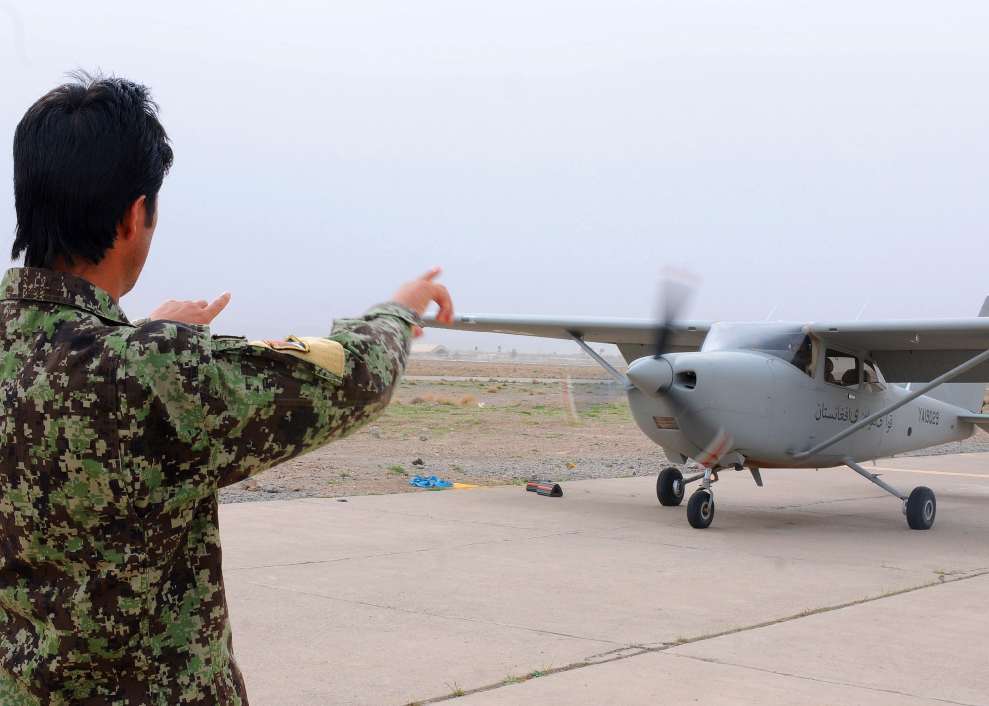 An Afghan air force crew chief gives the start the engine signal to AAF Lt. Emal Azizi, during a flight in a Cessna 182 aircraft at Shindand Air Base, Afghanistan, March 24, 2012. Azizi was one of three student pilots to perform Afghanistan’s first fixed-wing undergraduate pilot training flights in more than 30 years. (U.S. Air Force photo by Staff Sgt. Nadine Y. Barclay)

