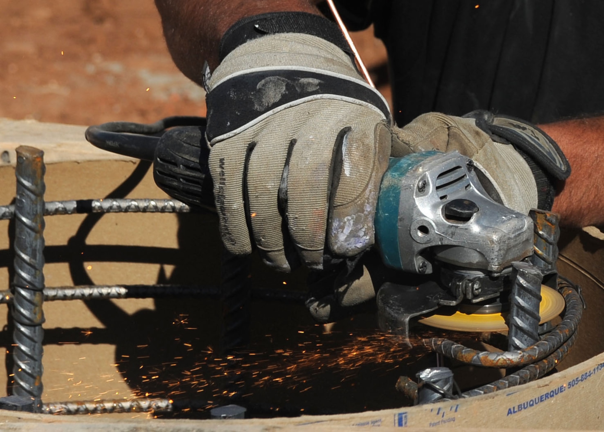 A construction worker uses an electric saw to cut steel bars in the swimming pool construction site at Cannon Air Force Base, N.M., March 16, 2012. The contractors have set a goal to have Cannon's Liberty pool completed by Memorial Day weekend. (U.S. Air Force photo by Airman 1st Class Eboni Reece)