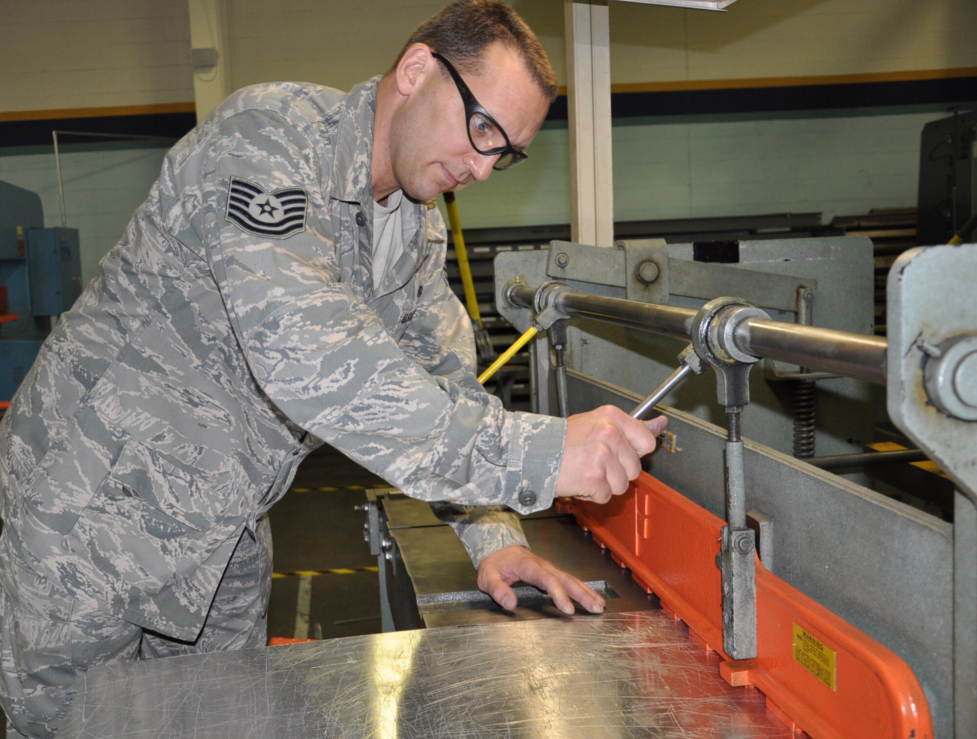 Tech. Sgt. Chad Marx, an aircraft structural maintainer with the 931st MXS, clamps a portion of sheet metal to a foot shear to build a galley for a KC-135 Stratotanker. (Air Force photo by Brannen Parrish)