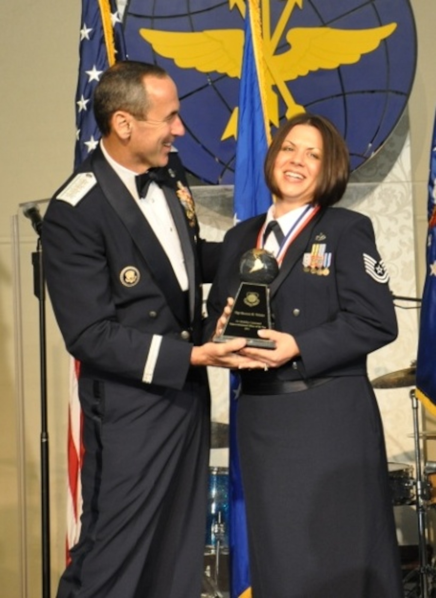 JOINT BASE McGUIRE-DIX-LAKESURST, N.J. -- Gen. Ray Johns, Air Mobility Command commander, presents the award for Noncommissioned Officer of the Year to Tech. Sgt. Shannon Webster, of the 521st Air Mobility Operations Wing, Ramstein AB, Germany, during the AMC Outstanding Airman of the Year banquet that took place at Scott AFB, Ill., March 21. Webster led six visits where she evaluated 514 civilians and oversaw $31 million in contracted operations as a Navy technical advisor in AMC’s largest Navy air terminal program. (U.S. Air Force photo by 1st Lt. Sybil Taunton, U.S. Air Force Expeditionary Center Public Affairs)