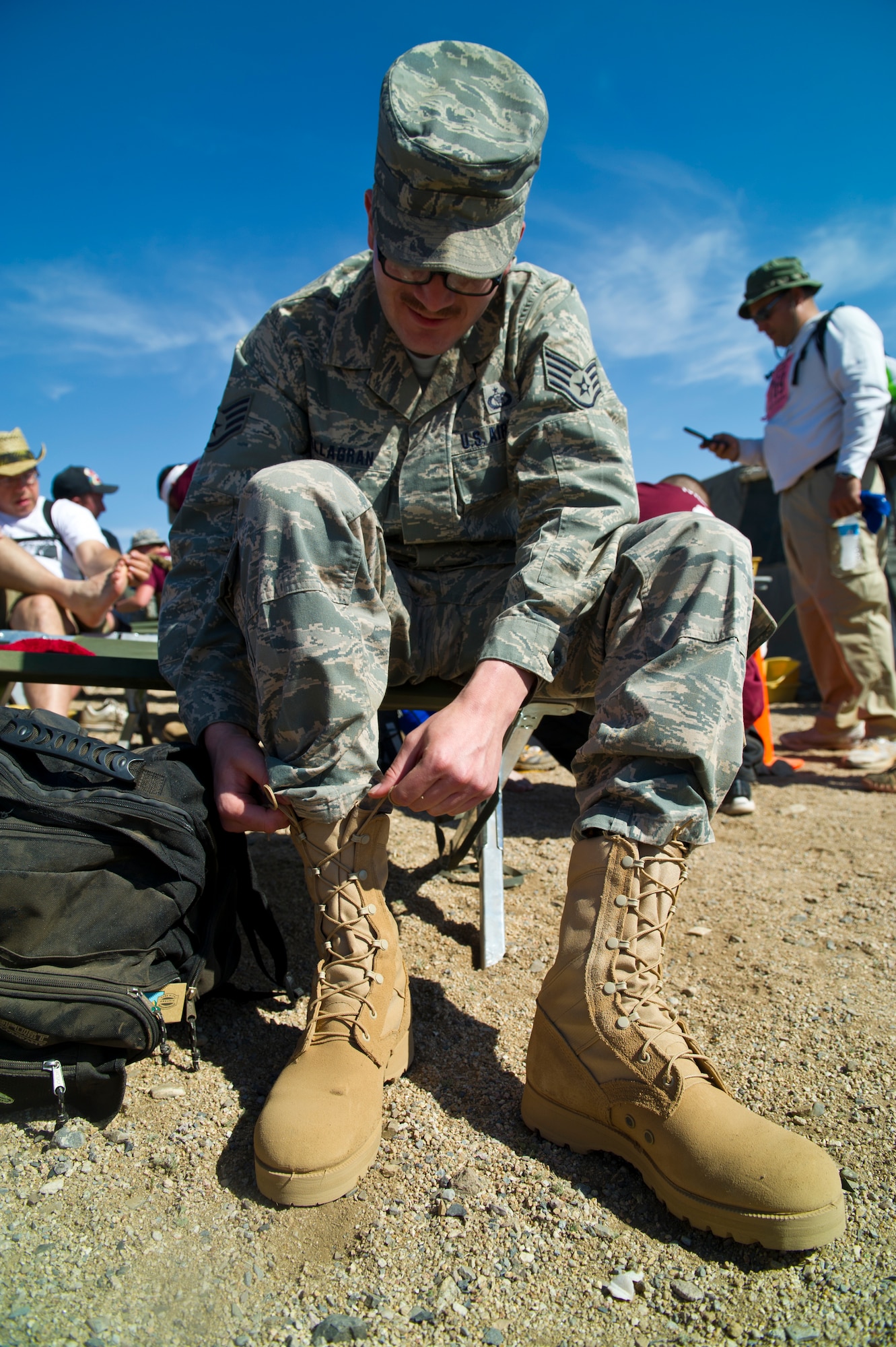 WHITE SANDS MISSILE RANGE, N.M. – U.S. Air Force Staff Sgt. Mark Villagran, 550th Special Operations Squadron aviation resource manager from Kirtland Air Force Base, N.M., laces up his boot after checking for blisters at a rest stop along the course of the Bataan Memorial Death March here March 25. Ricardo Gutierrez, 37, of Converse, Texas, finished the 26.2-mile marathon first in the military - light category, with a chip time of 4:21:35; Toby Angove, 39, of Indiana, Pa., finished first in the military - heavy category, with a chip time of 4:40:29. (U.S. Air Force photo by Airman 1st Class Daniel E. Liddicoet/Released)