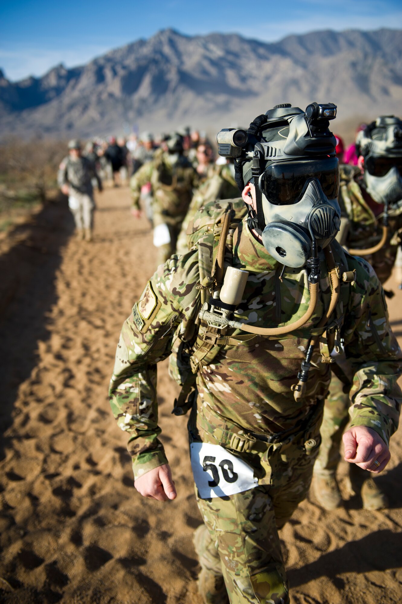 WHITE SANDS MISSILE RANGE, N.M. – Participants donning gas masks compete in the team category of the Bataan Memorial Death March here March 25. The event included categories of: civilian - light; civilian - heavy, with a 35-pound backpack; military - light; military - heavy, with a 35-pound backpack; Reserve Officers' Training Corps - light; and ROTC - heavy, with a 35-pound backpack. (U.S. Air Force photo by Airman 1st Class Daniel E. Liddicoet/Released)
