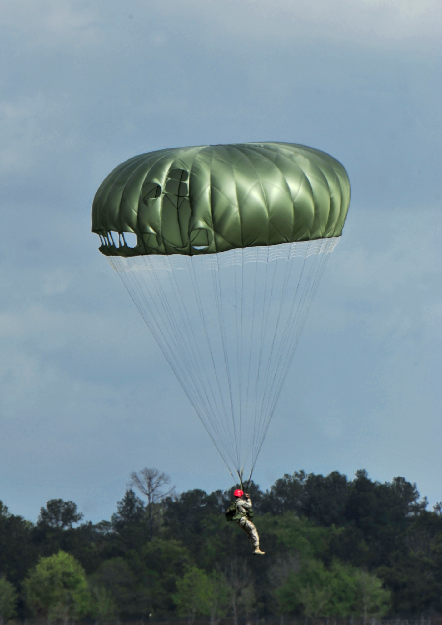 U.S. Air Force Senior Airman Ryan Godar, 823rd Base Defense Squadron, parachutes from the sky at Moody Air Force Base, Ga., March 21, 2012. After one completes the Basic Army Airborne Course, it’s tradition in the 820th Base Defense Group for new graduates to get their faces painted red and to wear a red helmet for their first jump with the unit. (U.S. Air Force photo by Staff Sgt. Stephanie Mancha/Released)