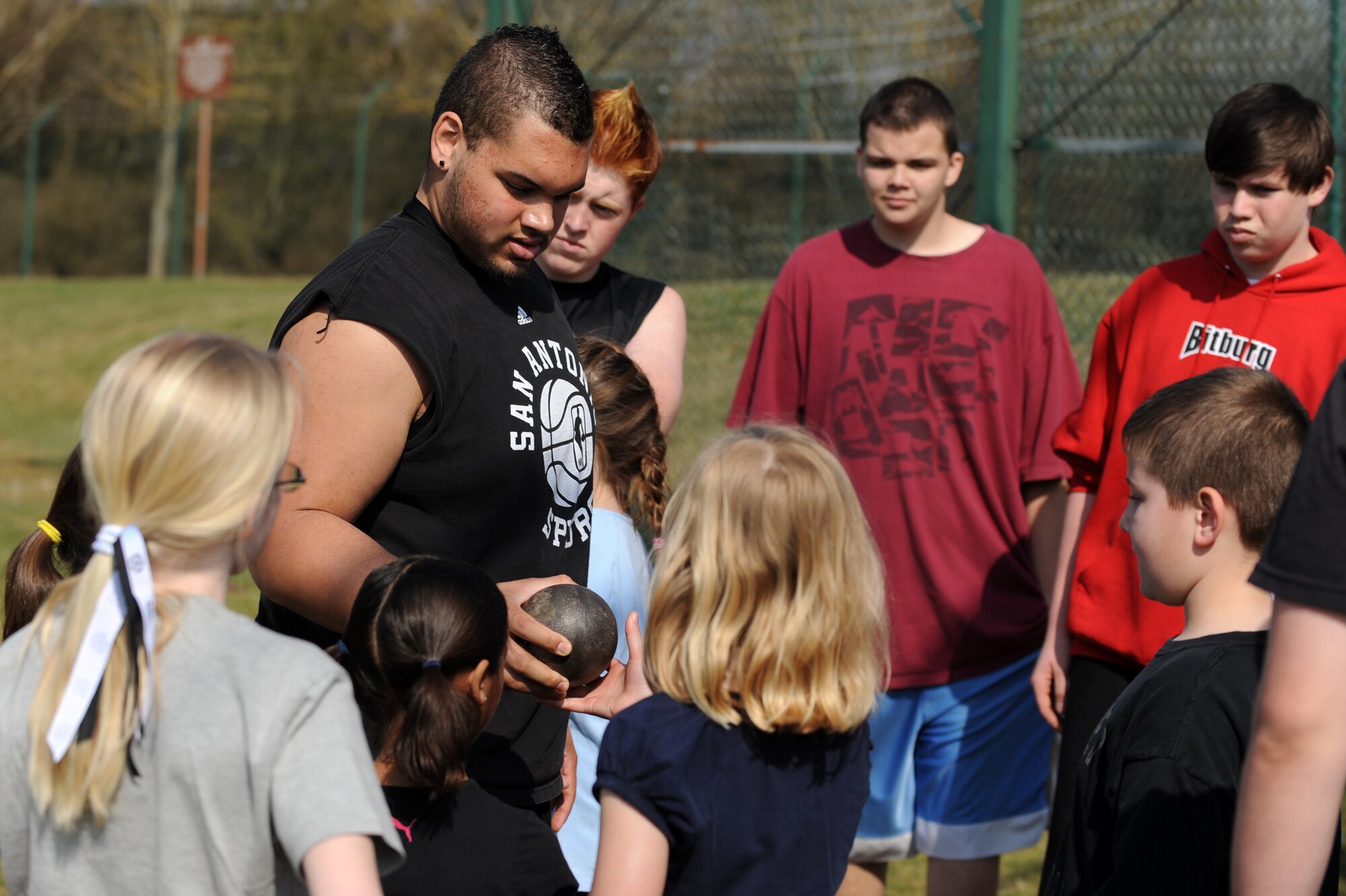 BITBURG ANNEX, Germany – Colton Engelmeier, son of Master Sgt. Eric Hall, 52nd Communications Squadron, shows the metal ball used in shot put to Spangdahlem and Bitburg Elementary and Middle School students during a track and field day at the Bitburg High School track here March 24. The BHS track team hosted the event to introduce the first- through sixth-grade students to the sport’s events. The team taught students about track and field to promote interest in staying active and healthy. (U.S. Air Force photo by Airman 1st Class Matthew B. Fredericks/Released)