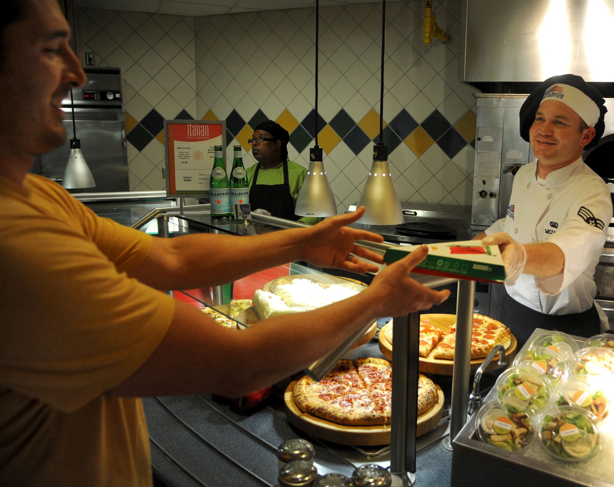 Senior Airman Brady McDede, 6th Force Support Squadron food service technician, hands a slice of pizza to Citi Bank Employee, Kevin Hausler during the lunch hour at the Citi Bank corporate building in Tampa, Fla., March 23, 2012. McDede has been training with civilian chefs to help improve the dining conditions on MacDill Air Force Base, Fla. (U.S. Air Force photo by Airman Basic David Tracy)