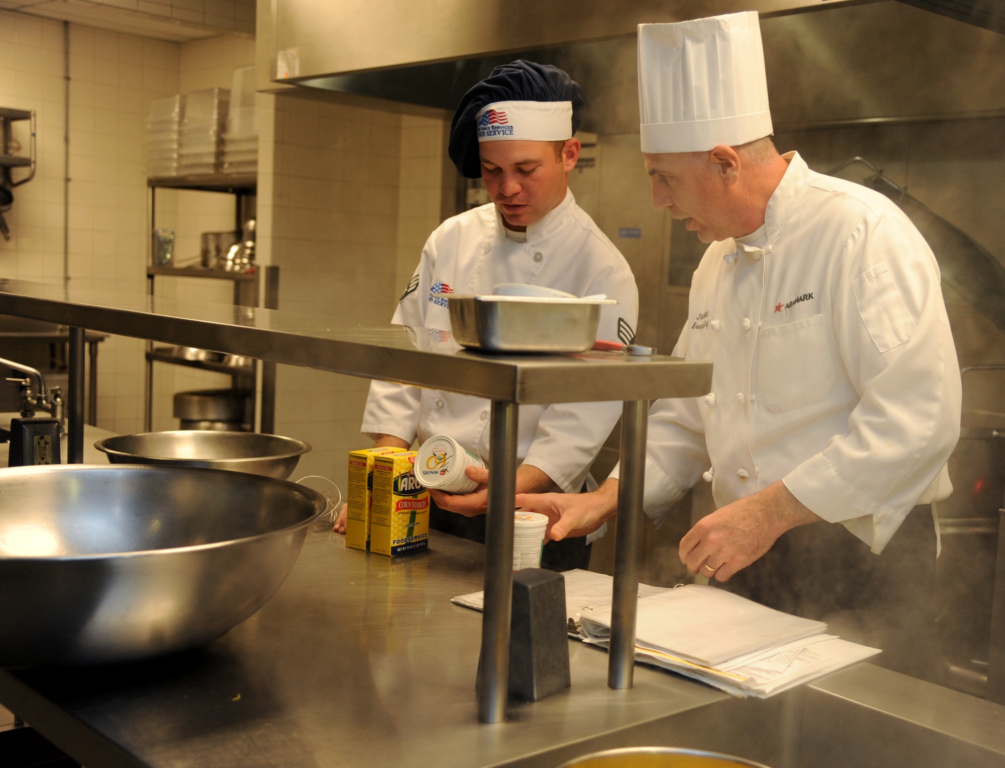 John Hackett, executive chef, discusses a recipe for Manhattan clam chowder with Senior Airman Brady McDede, 6th Force Support Squadron food service technician, at the Citi Bank corporate building in Tampa, Fla., March 23, 2012. McDede has been training with civilian chefs to help improve the dining conditions on MacDill Air Force Base, Fla. (U.S. Air Force photo by Airman Basic David Tracy)