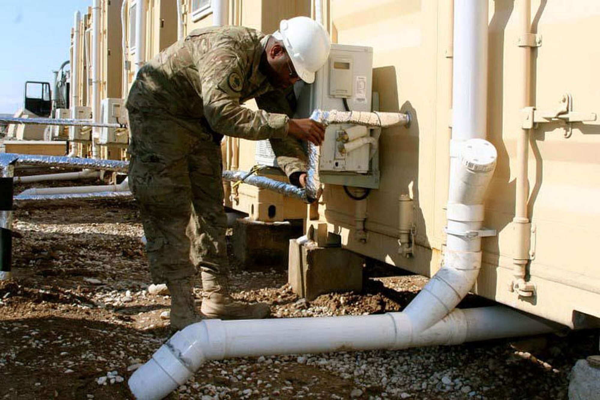 Air National Guard Staff Sgt. Arthur Mitchell, a civil engineer with the 577th Expeditionary Prime BEEF (Base Emergency Engineer Force) Squadron at Camp Marmal, checks a pipe of a Latrine-Shave-Shower (LSS) unit for plumbing issues. The 577th EPBS serves the role of civil engineer throughout Afghanistan and is a part of the International Security Assistance Force. (Photo by U.S. Navy Lt. j.g. Cheryl Collins, RC-North Public Affairs)