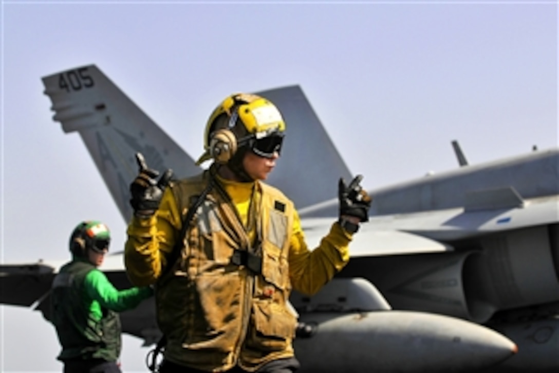 U.S. Navy Seaman Cody Ottmo directs an F/A-18C Hornet on the flight deck of the USS Carl Vinson in the Arabian Sea on March 15, 2012.  Ottmo is an aviation boatswain's mate (Handling) assigned to the Air Department's V-1 Division.  