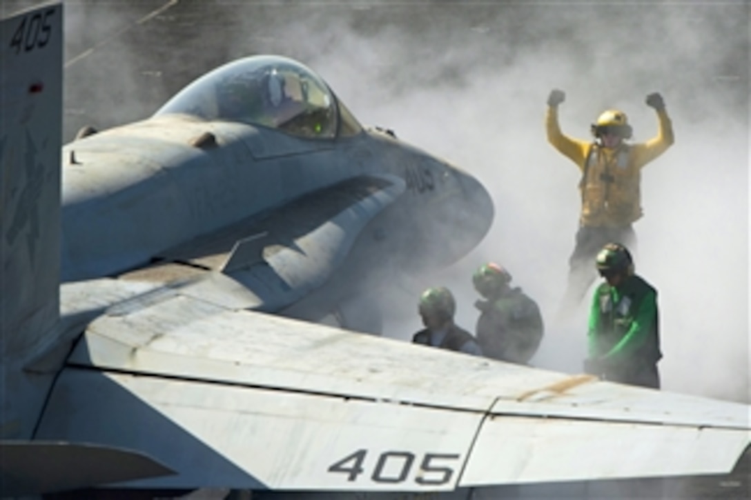 U.S. Navy Petty Officer 3rd Class Eric Welsh directs an F/A-18C Hornet onto the bow catapults for launch on the flight deck aboard the aircraft carrier USS Carl Vinson in the Persian Gulf on March 5, 2012.  Welsh is an aviation boatswain's mate, handling.  