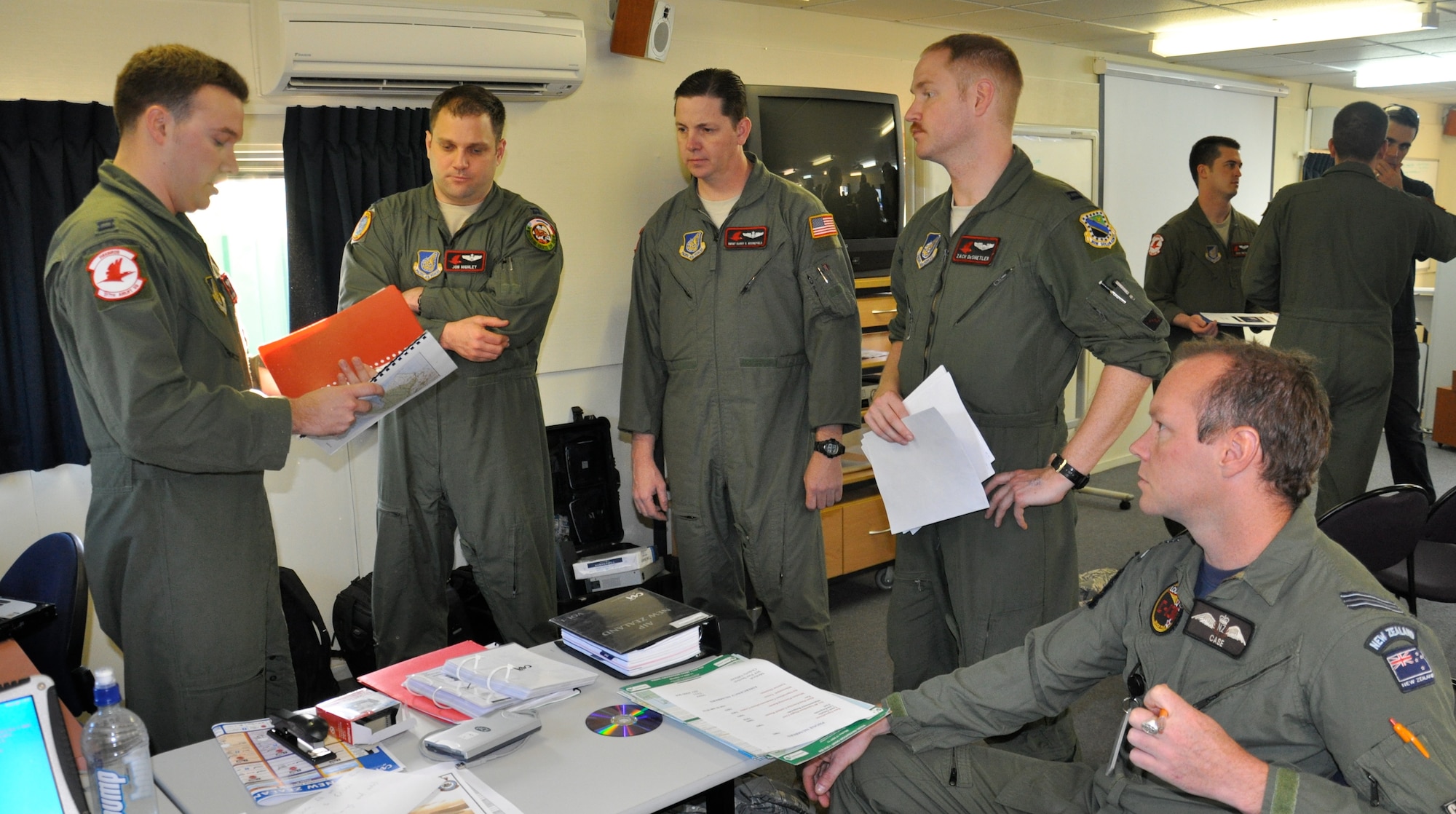 Aircrew from the 517th Airlift Squadron assigned to Joint Base Elmendorf-Richardson, Alaska discuss mission plans with their Royal New Zealand Air Force mission liaison, Flight Lieutenant Gaerth Russell before their first mission during Exercise KIWI FLAG. Aircrews are working with their RNZAF counterparts as the plan, execute and debrief airdrop missions to develop and expand combined airlift capabilities with regional partners. (U.S. Air Force photo by Capt. Rebecca Heyse/Released)