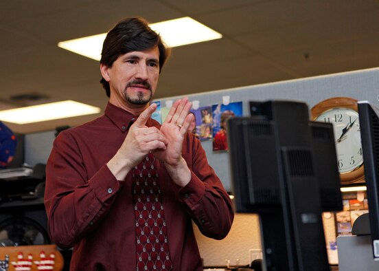 Mike Botte, 95th Communications Squadron Information Technology professional, signs during a call made March 23, 2012, via the new video communication device. The new video communication devices will enable deaf and hard-of-hearing employees to make calls via a monitor on their phone connected to a relay interpreter. (U.S. Air Force photo by Jet Fabara)  