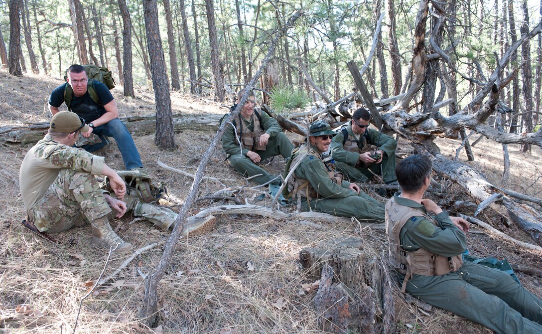 Senior Airman Brandon Dunphy (left), 28th Operations Support Squadron Survival Evasion Rescue Escape specialist, instructs aircrew members to take cover behind a tree during a survival exercise at Sturgis Training Compound, Sturgis, S.D., March 22, 2012. The two aircrew teams were required to navigate to different points throughout the compound in order to be rescued. (U.S. Air Force photo by Airman 1st Class Alystria Maurer/Released)