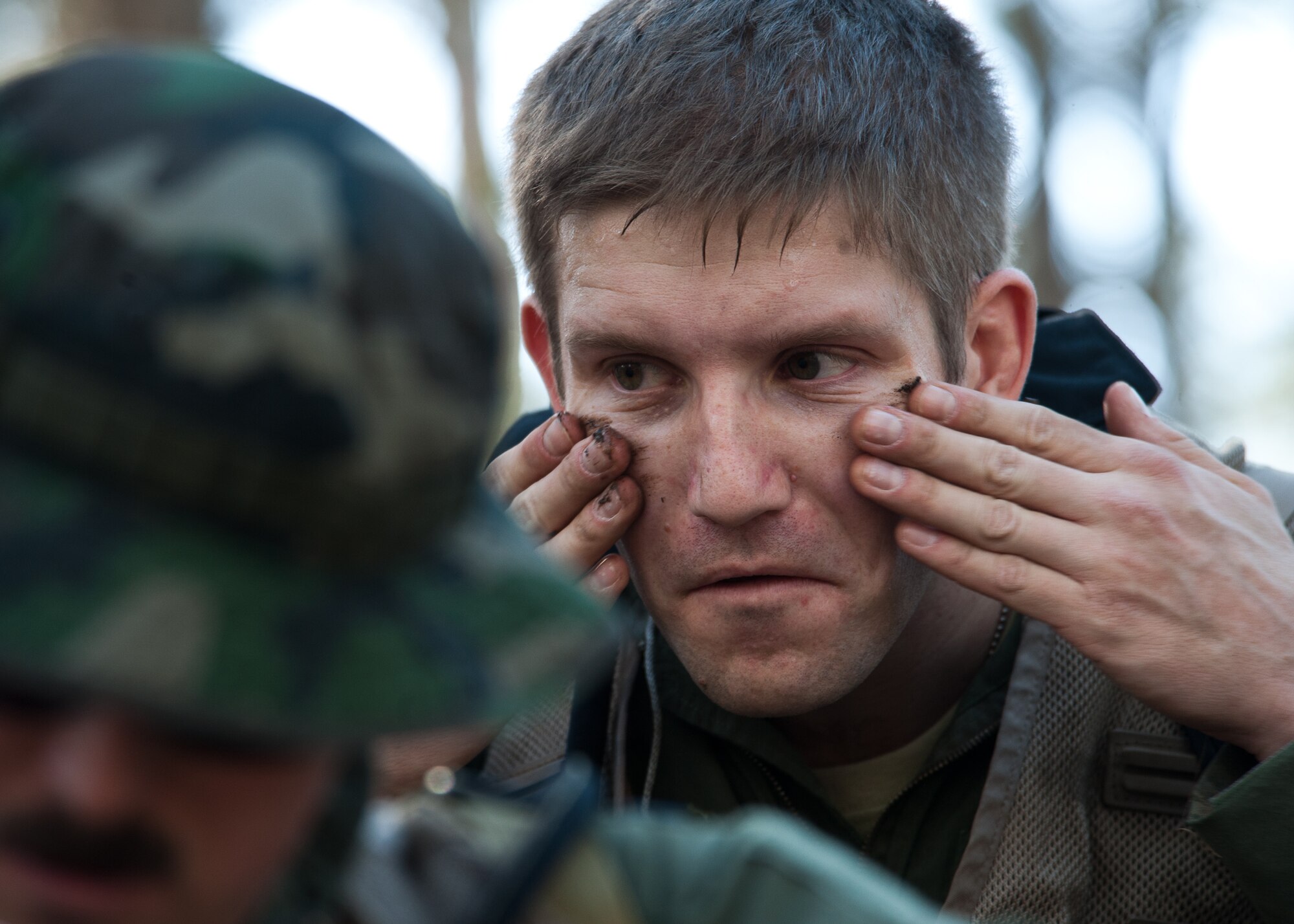 Capt. Christopher Rumpf, 37th Bomb Squadron instructor pilot, applies mud to his face as camouflage during the combat survival training at Sturgis Training Compound, Sturgis, S.D., March 22, 2012. Each member of the team applied camouflage and found concealment to help the entire team survive until rescue. (U.S. Air Force photo by Airman 1st Class Alystria Maurer/Released)