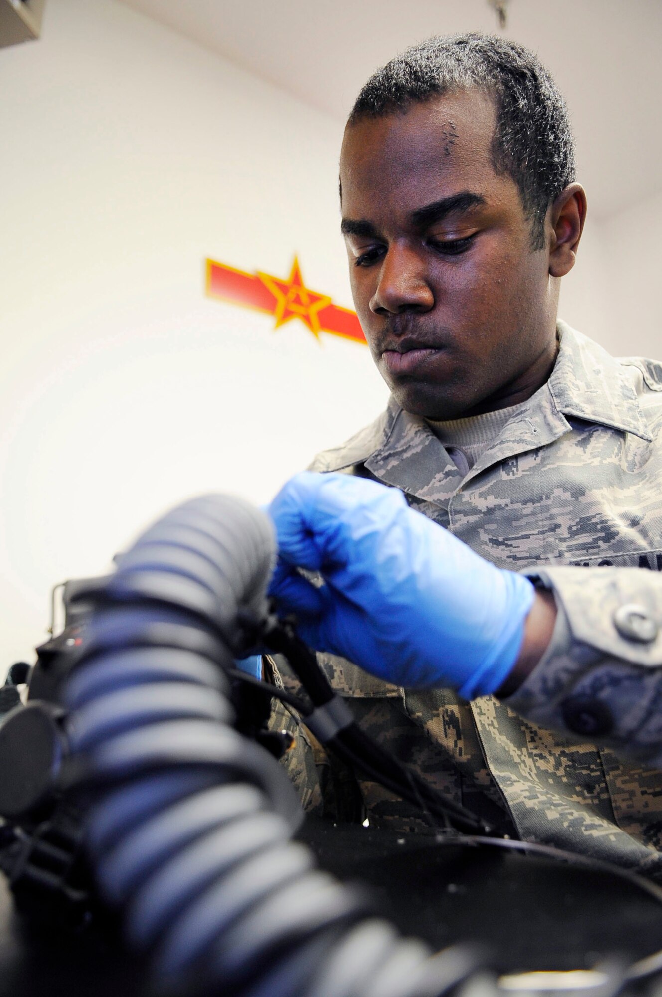 U.S. Air Force Airman 1st Class Michael Brooks, 354th Operations Support Squadron aircrew flight equipment technician, tacks bayonet straps on a Mask Breathing Unit March 21, 2012, Eielson Air Force Base, Alaska. The MBU provides breathing to aircrew under G-force conditions helping reduce the risk of gravity induced loss of consciousness. (U.S. Air Force photo/Staff Sgt. Jim Araos)