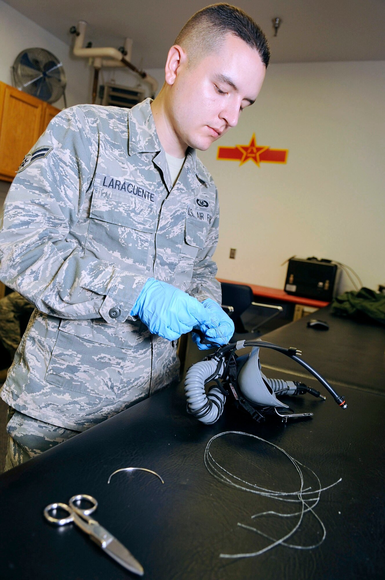 U.S. Air Force Airman 1st Class Osvaldo Laracuente, 354th Operations Support Squadron aircrew flight equipment technician, tacks bayonet straps on a Mask Breathing Unit March 21, 2012, Eielson Air Force Base, Alaska. During flight, bayonet straps ensure the MBU stays donned to the aircrew helmet protective system. (U.S. Air Force photo/Staff Sgt. Jim Araos) 