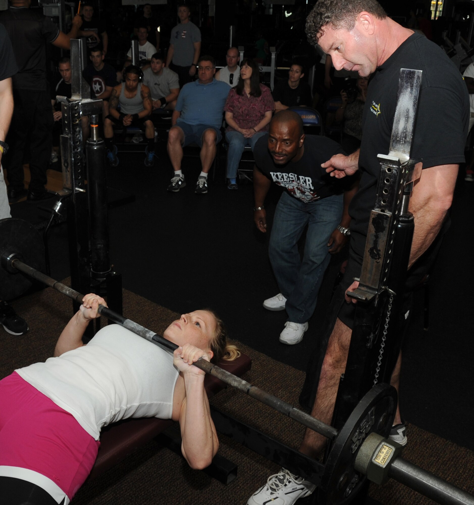 Second Lt. Charlotte Trott, 81st Inpatient Operation Squadron, takes her turn during the bench press portion of the muscle mania competition, while Al Watkins, 81st Infrastructure Division, serves as the judge and Robert Reville spots her March 24, 2012, at the triangle fitness center, Keesler Air Force Base, Miss.  Trott placed second overall in the women’s division.  (U.S. Air Force photo by Kemberly Groue)