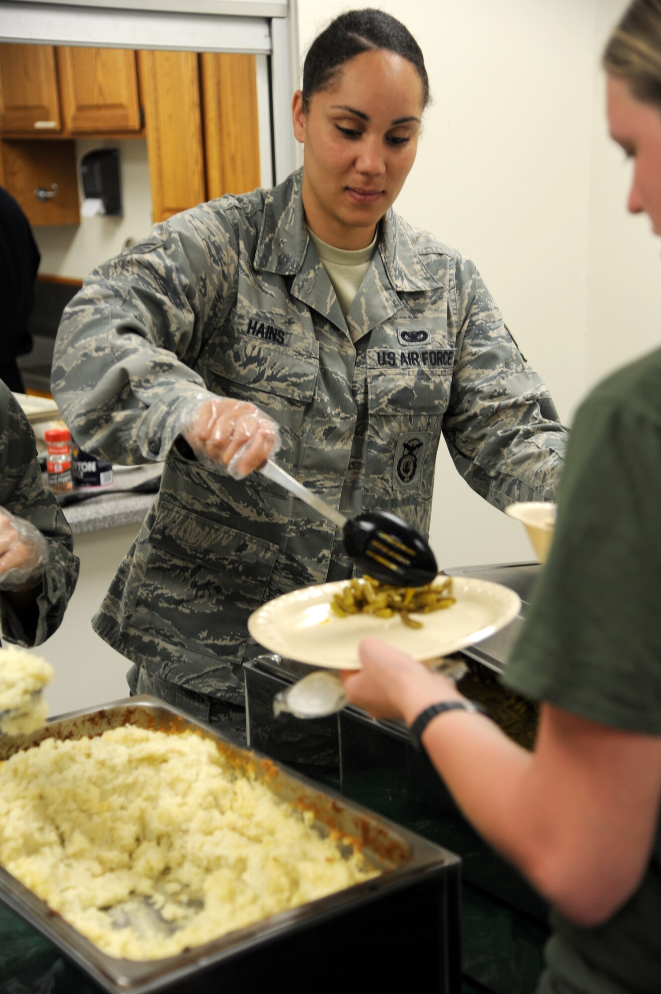Senior Airman Tynisia Haines, with the 71st Security Forces Squadron, serves green beans during this month’s Singles’ International Gourmet Meal Opportunity in the Community Chapel Activity Center at Vance Air Force Base, Okla., March 26. (U.S. Air Force photo/ Airman 1st Class Frank John Casciotta) 