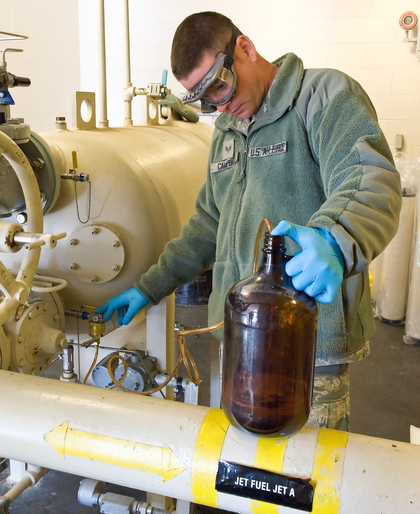 Senior Airman Timothy Campbell, a fuel lab technician with the 436th Logistics Readiness Squadron, draws a sample of Jet A fuel from a pipe March 27, 2012, at Dover Air Force Base, Del. The sample will be tested at the fuels lab for impurities and contaminates before being pumped to the flight line for a re-fuel. (U.S. Air Force photo by Roland Balik) 