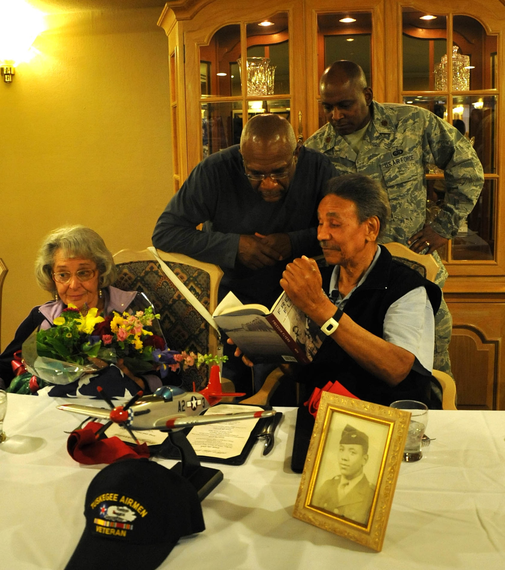 Maj. Arthur Tigney, 943rd Mission Support Flight Commander and Mr. Jeffrey Howery look over a book on the Tuskegee Airmen with Mr. Ralph Stewart after his flag presentation ceremony. Mr. Stewart was a mechanic during World War II on the B-25 and B-26 bombers as a Tuskegee Airman. (U.S. Air Force Photo/ Master Sgt. Luke Johnson)