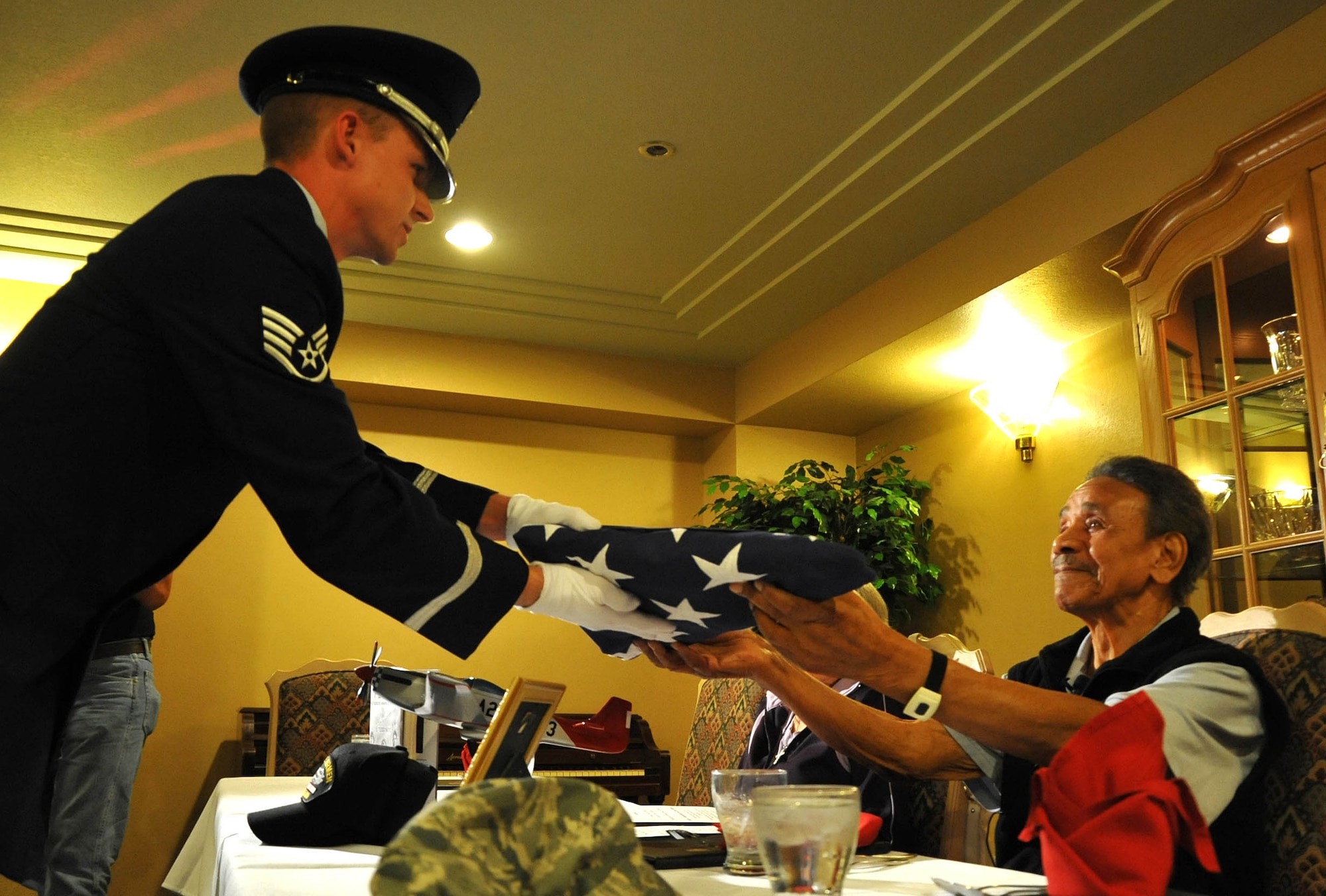 A member of the Davis Monthan Air Force Base Honor Guard presents Mr. Ralph Stewart an American Flag to honor his service in the U.S. Army Air Corps during World War II. Mr. Stewart was a mechanic on the B-25 and B-26 bombers as a Tuskegee Airman. (U.S. Air Force Photo/ Master Sgt. Luke Johnson)