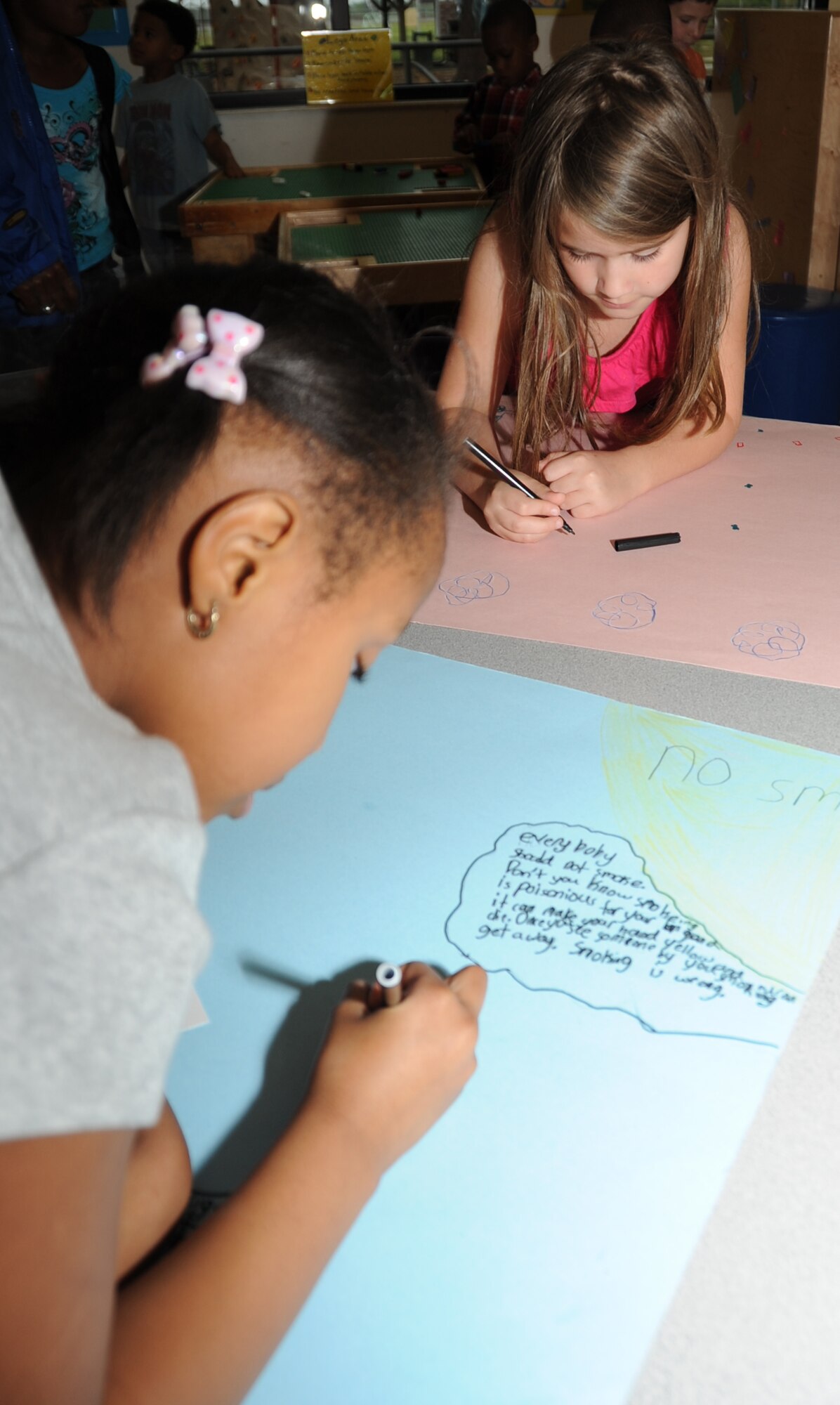 Seven-year-olds Tineka Adams and Sofia Kiddy, decorate a “Kick Butts Day” poster at the youth center March 19, 2012, at Keesler Air Force Base, Miss.  The anti-smoking event poster display was judged March 21, with a prize awarded to the first place winners in each age category. Tineka is the daughter of retired Garfield and Vivienne Adams.  Sofia is the daughter of Aimee and Tech. Sgt. William Kiddy, 81st Medical Group.  Sofia placed second in her age group category.  (U.S. Air Force photo by Kemberly Groue)