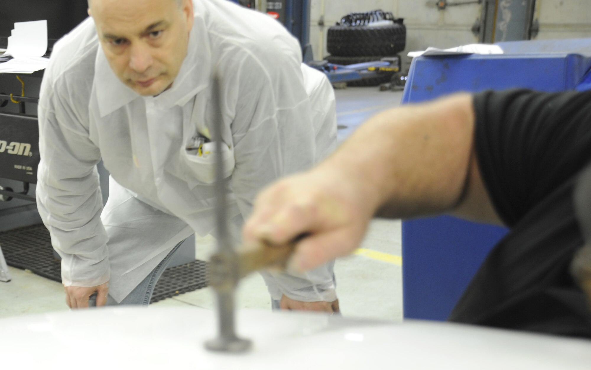 Chief Master Sgt. Tony Tingley, 89th Airlift Support Group superintendent, watches Harvey McKenzie, auto body technician, repair a dent at an auto body class at the Andrews Auto Hobby Center on March 25.  Using the skills learned in the class and the tools and facilities available at the hobby center, members are able to make repairs themselves, saving them a considerable amount of money.  (U.S. Air Force photo/Senior Airman Torey Griffith)(released)