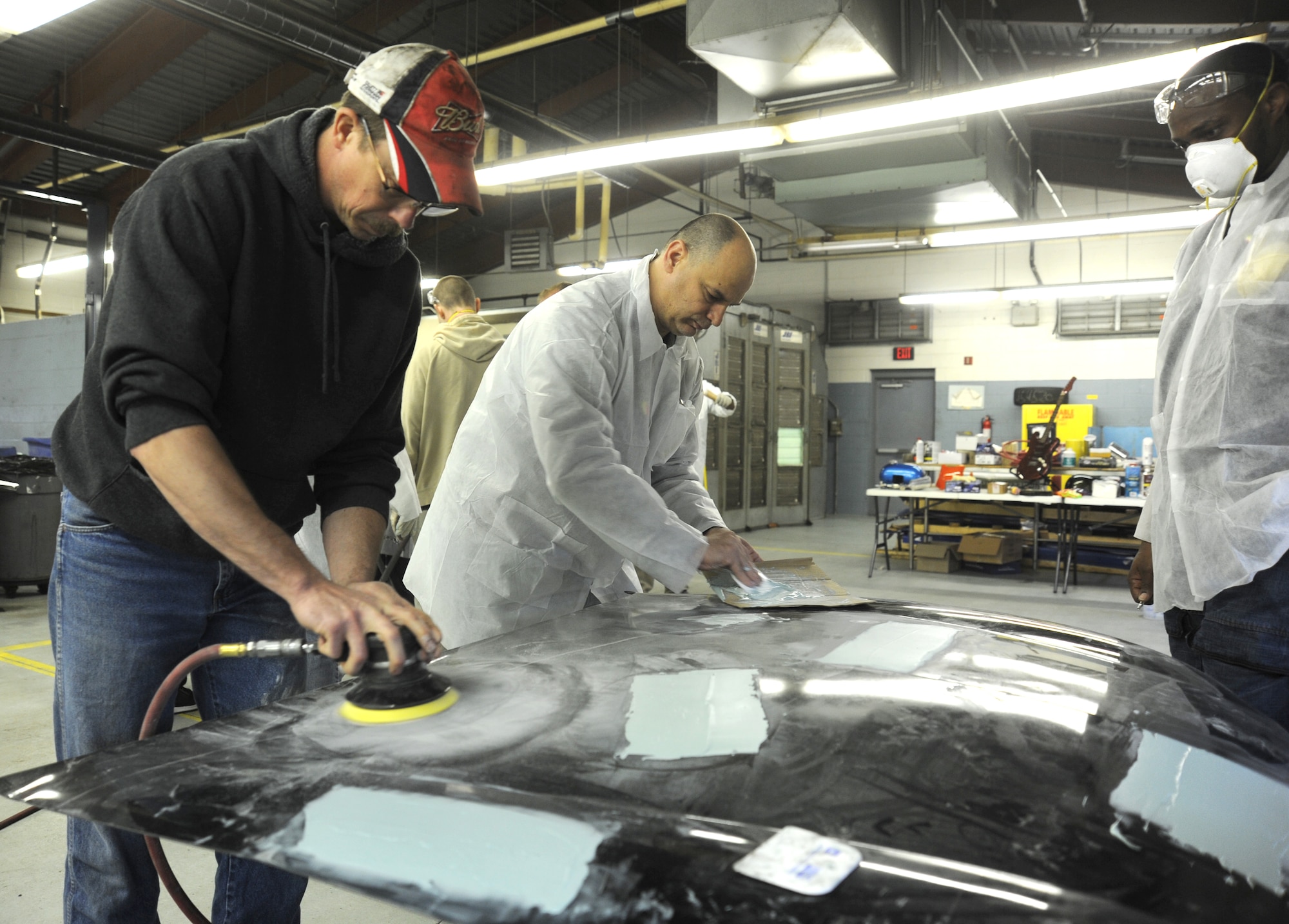 Team Andrews members repair dents on a car hood during an auto body class at the Andrews Auto Hobby Center on March 25.  Employees from Maaco of Waldorf donated time and materials to teach the basics of repairing dents, sanding, priming and refinishing panels.  With the equipment they provided, Team Andrews members will be able to refinish their cars themselves at the hobby shop versus taking their cars to a shop to have the work done.  (U.S. Air Force photo/Senior Airman Torey Griffith)(released)