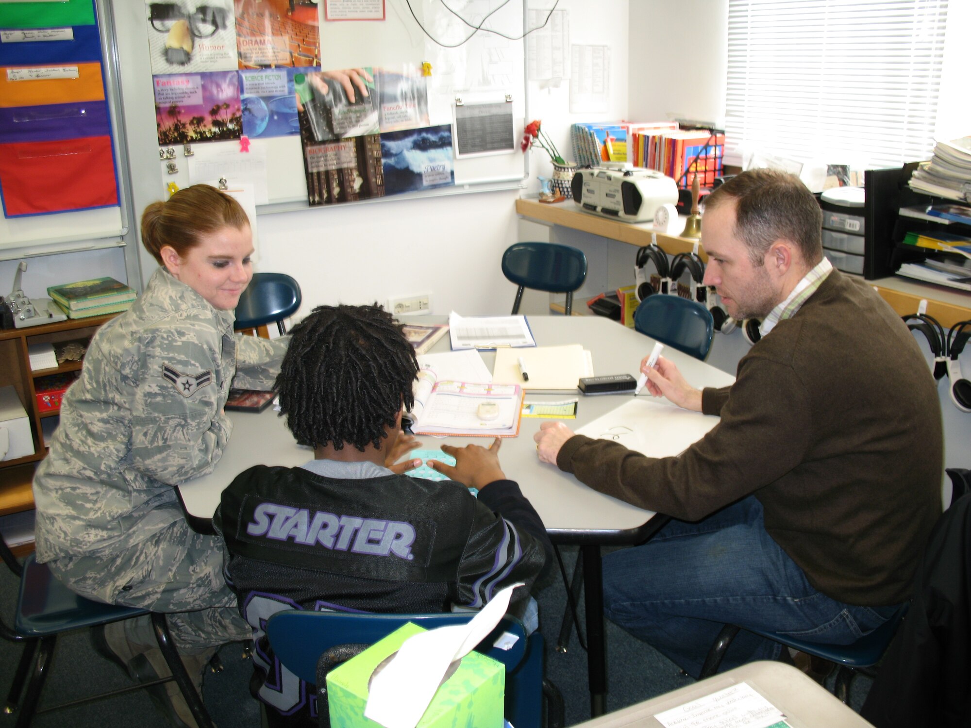 Tech Sgt. Gregory Love, 31st Contracting Squadron infrastructure NCOIC, and Airman 1st Class Jessica Ray, 31st CONS contract specialist mentor fifth-grader Kishaun Kimble and help him with math problems during a tutoring session at Aviano Elementary School. Students having difficulty in math and reading are receiving help from Airmen with the start of a  new mentorship program. The program matches a volunteer with a student scoring in the lower percentage of the Terra Nova standardized test. The tutor attends training and meets with the student’s family to establish a one-on-one tutoring schedule, focusing on the areas the student is having the most trouble in. (Courtesy photo)