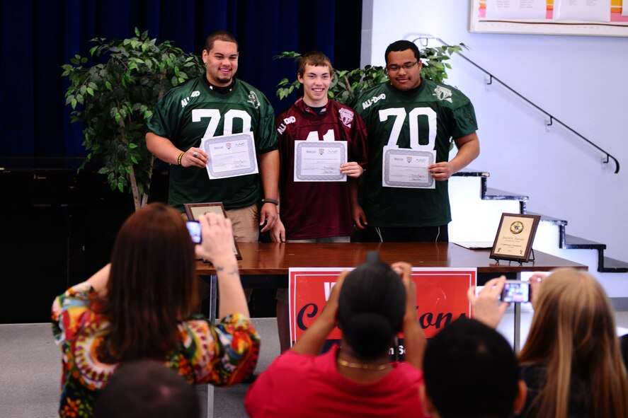 BITBURG ANNEX, Germany – Colton Engelmeier, left, Matthew Flood, center, and Darian Billups pose for photos to commemorate their selection to the Military.com All-Department of Defense Team at Bitburg High School here March 27. The team is made up of 24 football players who are children of service members stationed throughout the world. Military.com is a military and veteran membership organization that connects service members, military families and veterans to all the benefits of service. The BHS football team members received a certificate and a team jersey, and will attend an upcoming invitation-only 2012 Football University Camp, taught by NFL coaches and players. The team members will find out at a later date which one of the 45 camps they will be invited to attend. (U.S. Air Force photo by Airman 1st Class Matthew B. Fredericks/Released)