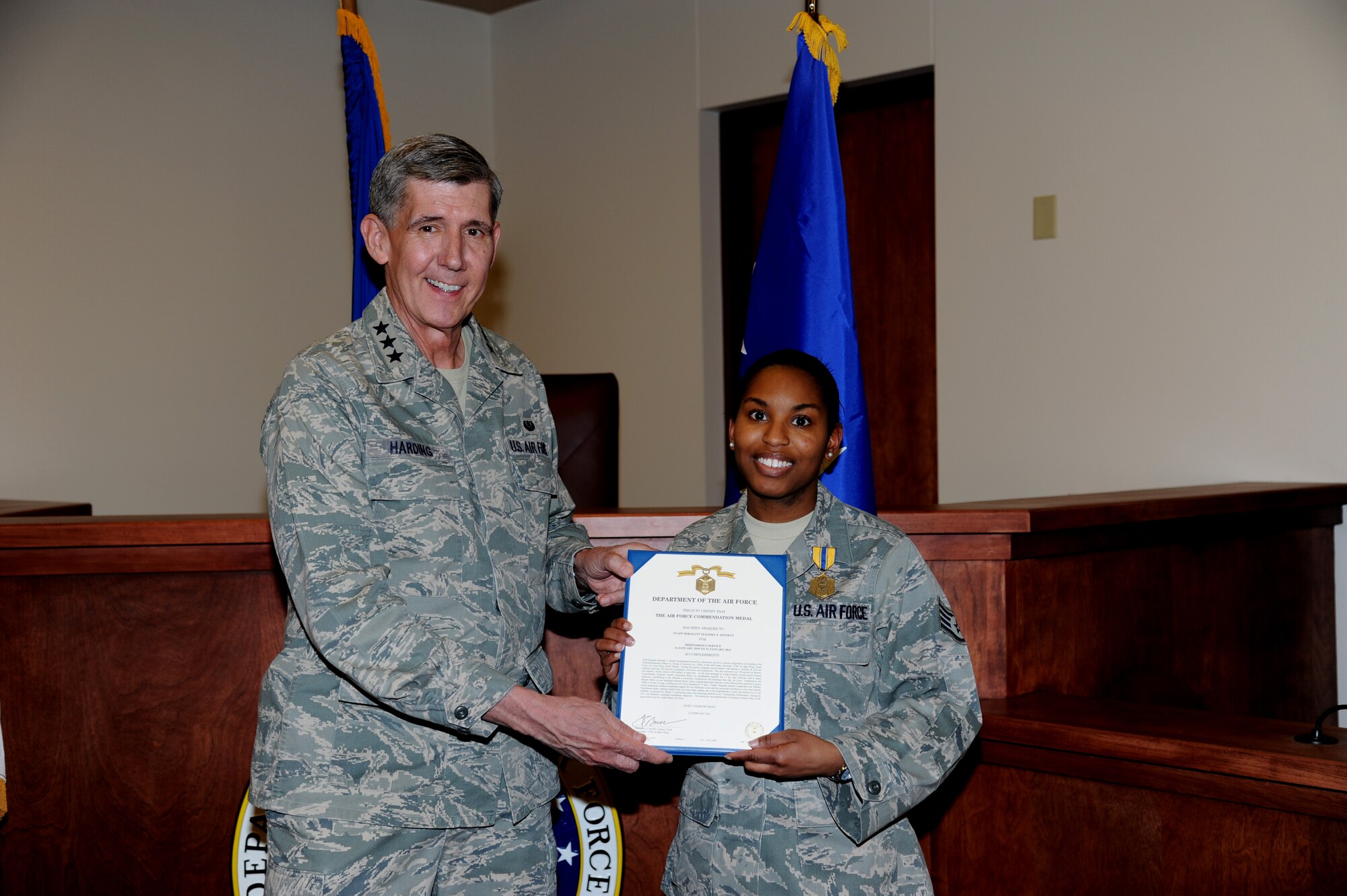 Lt. Gen. Richard C. Harding, The Judge Advocate General of the Air Force, presents an Air Force Commendation Medal to Staff Sgt. Malisha Jennett, Area Defense Council, during a visit to Grand Forks Air Force Base, N.D., on March 13. (U.S. Air Force photo by Staff Sgt. Amanda N. Grabiec)