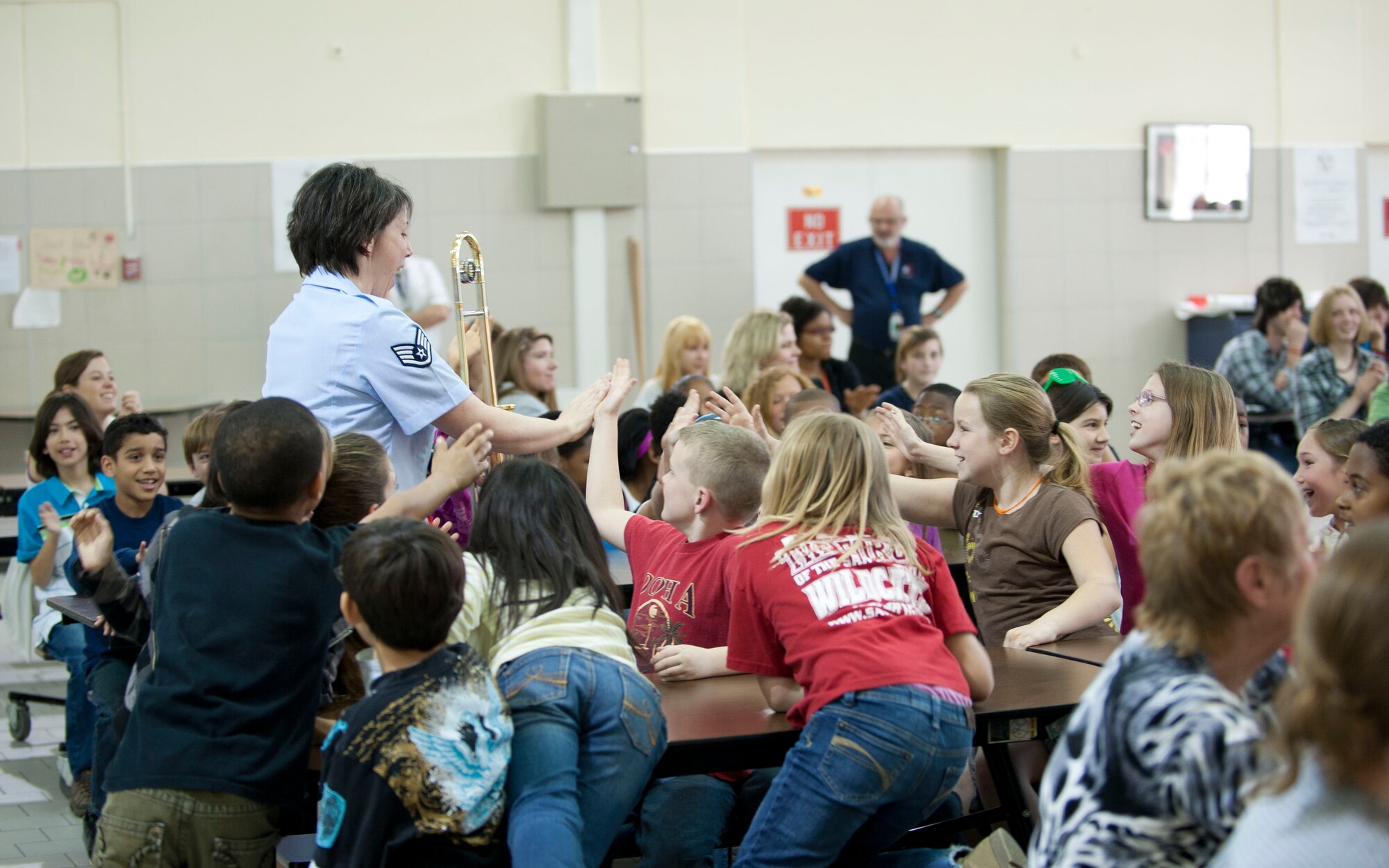 Staff Sgt. Saundra Sininger, trombone player for U.S. Air Forces in Europe Band "Wings of Dixie," high-fives children during a performance in the Incirlik Unit School multipurpose room March 22, 2012, at Incirlik Air Base, Turkey. Wings of Dixie performed several times for the school as part of the Music in Our Schools program and put on a show for members of Team Incirlik in the Club Complex ballroom March 23. (U.S. Air Force photo by Senior Airman Clayton Lenhardt/Released)