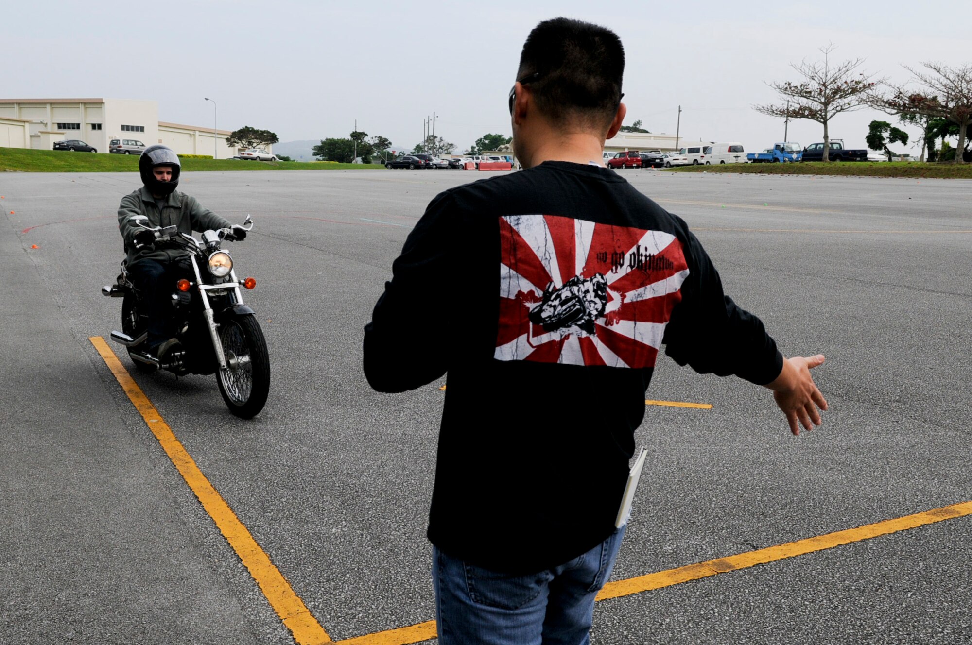 U.S. Air Force Tech. Sgt. Andy Chang, guest motorcycle safety course instructor from the 390th Intelligence Squadron, signals student Staff Sgt. Craig Virginia, 18th Security Forces Squadron patrolman, to stop for further instruction on shifting gears during a motorcycle safety course on Kadena Air Base, Japan, March 20, 2012. Basic, advanced and sport bike courses are offered on Kadena for those requiring them. (U. S. Air Force photo by Airman 1st Class Tara A. Williamson/Released)