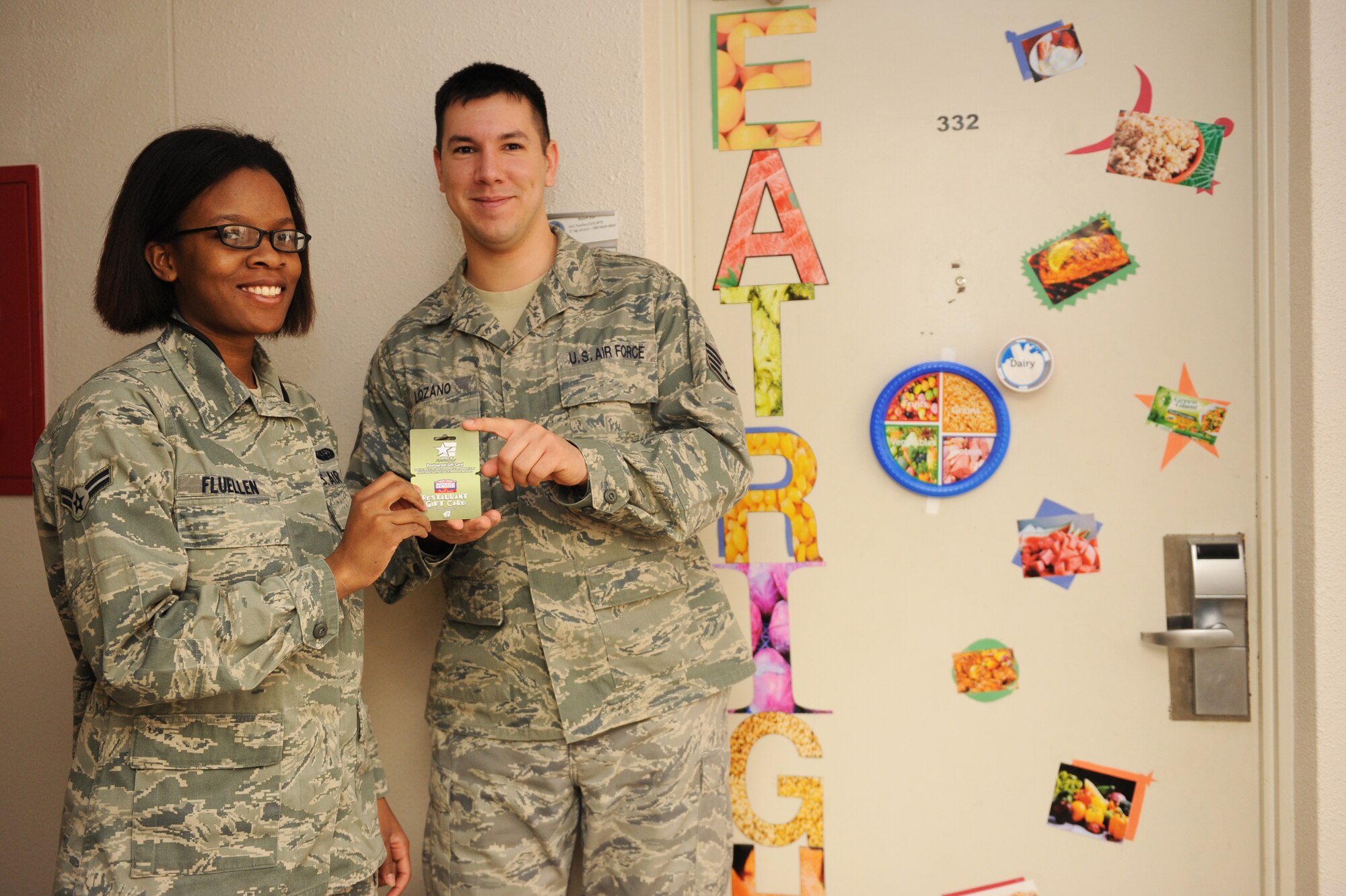 U.S. Air Force Staff Sgt. Anthony Lozano, right, 35th Aerospace Medical Squadron diet technician, presents Airman 1st Class Ariel Fluellen, 373rd Support Squadron radio frequency transmission systems technician, a $125 Army Air Force Exchange Service (AAFES) gift card for winning first place in the National Nutrition Month Dorm Door Decorating Contest at Misawa Air Base, Japan, March 27, 2012. The theme for the contest was, "Get your plate in shape."  It is also the theme for National Nutrition Month 2012, which puts focus on the balance of calories in everyday food choices. (U.S. Air Force photo by Airman 1st Class Kia Atkins/Released)