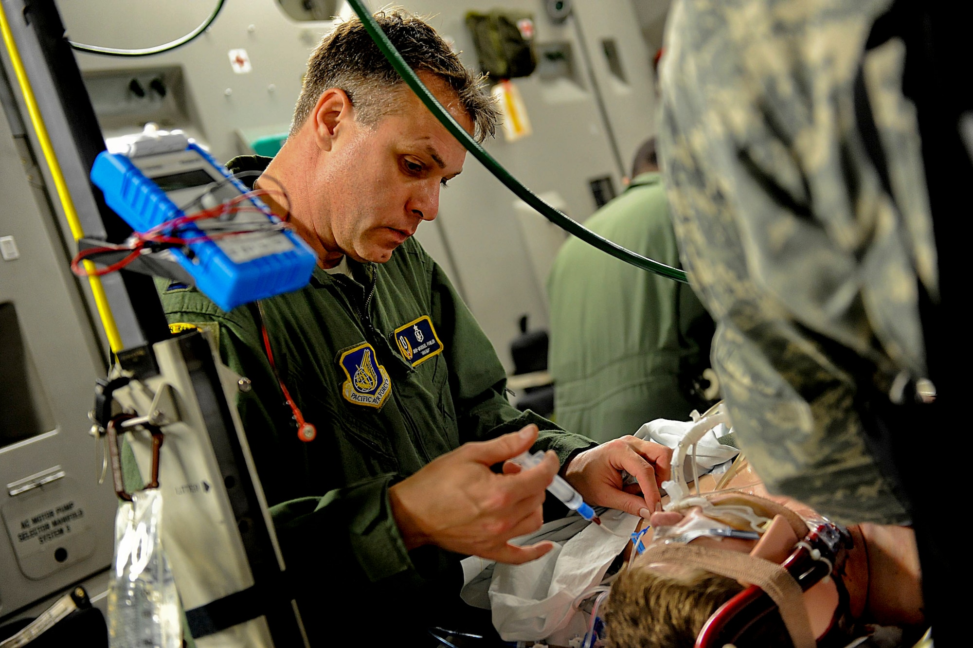 U.S. Air Force Capt. John-Michael Fowler, critical care air transportation nurse for Joint Base Pearl Harbor-Hickam, Hawaii, administers medication before an aero-medical evacuation on Kadena Air Base, Japan, March 26, 2012. The patient is a U.S. Marine who was being medically evacuated to Hawaii for further treatment. (U.S. Air Force photo by Airman 1st Class Brooke P. Beers/Released )