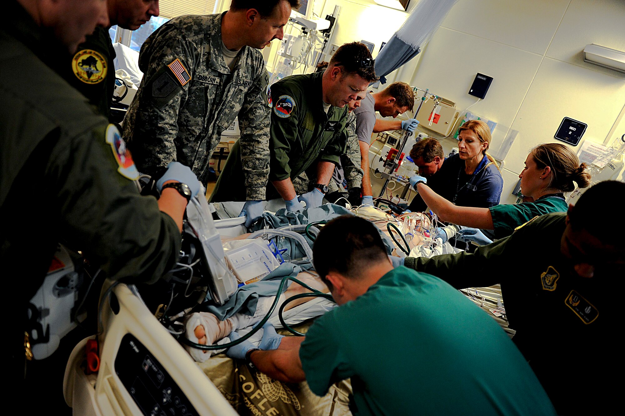 U.S. Army, Air Force and Navy personnel work as a team to move a Marine patient from his bed to a stretcher in order to transport him to Kadena Air Base from U. S. Naval Hospital Okinawa, Camp Lester, Japan, March 26, 2012. Although the team members and patient are not in the same branch of service, they all work together to perform the same mission; keeping the patient safe. (U.S. Air Force photo by Airman 1st Class Brooke P. Beers/Released)