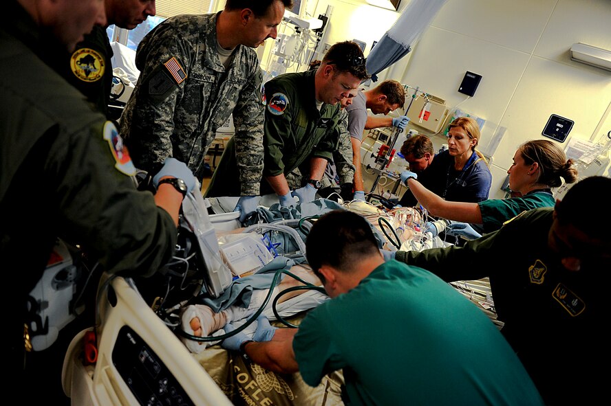 U.S. Army, Air Force and Navy personnel work as a team to move a Marine patient from his bed to a stretcher in order to transport him to Kadena Air Base from U. S. Naval Hospital Okinawa, Camp Lester, Japan, March 26, 2012. Although the team members and patient are not in the same branch of service, they all work together to perform the same mission; keeping the patient safe. (U.S. Air Force photo/Airman 1st Class Brooke P. Beers/Released) 

