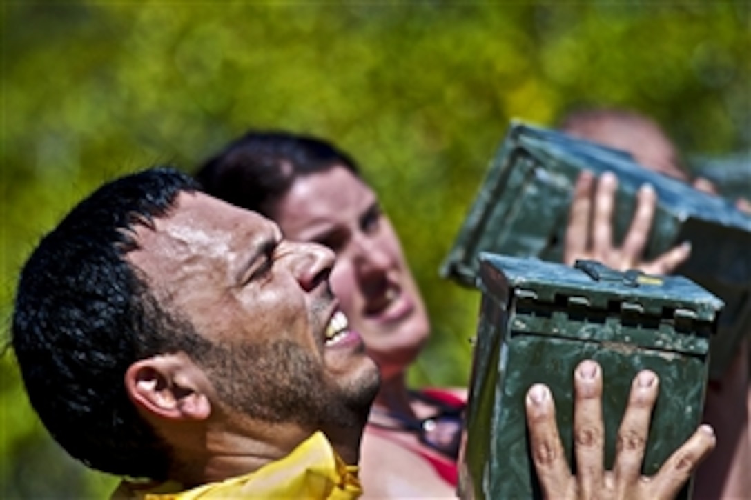A participant in the Miami Superhero Scramble struggles to press an ammo can over his head during the Marine Mile section of the obstacle course in Fort Lauderdale, Fla., March 24, 2012. The Superhero Scramble is 3.5 miles of rugged terrain with more than 18 obstacles, including major water crossings. The race tests the competitors’ resilience, strength and endurance.