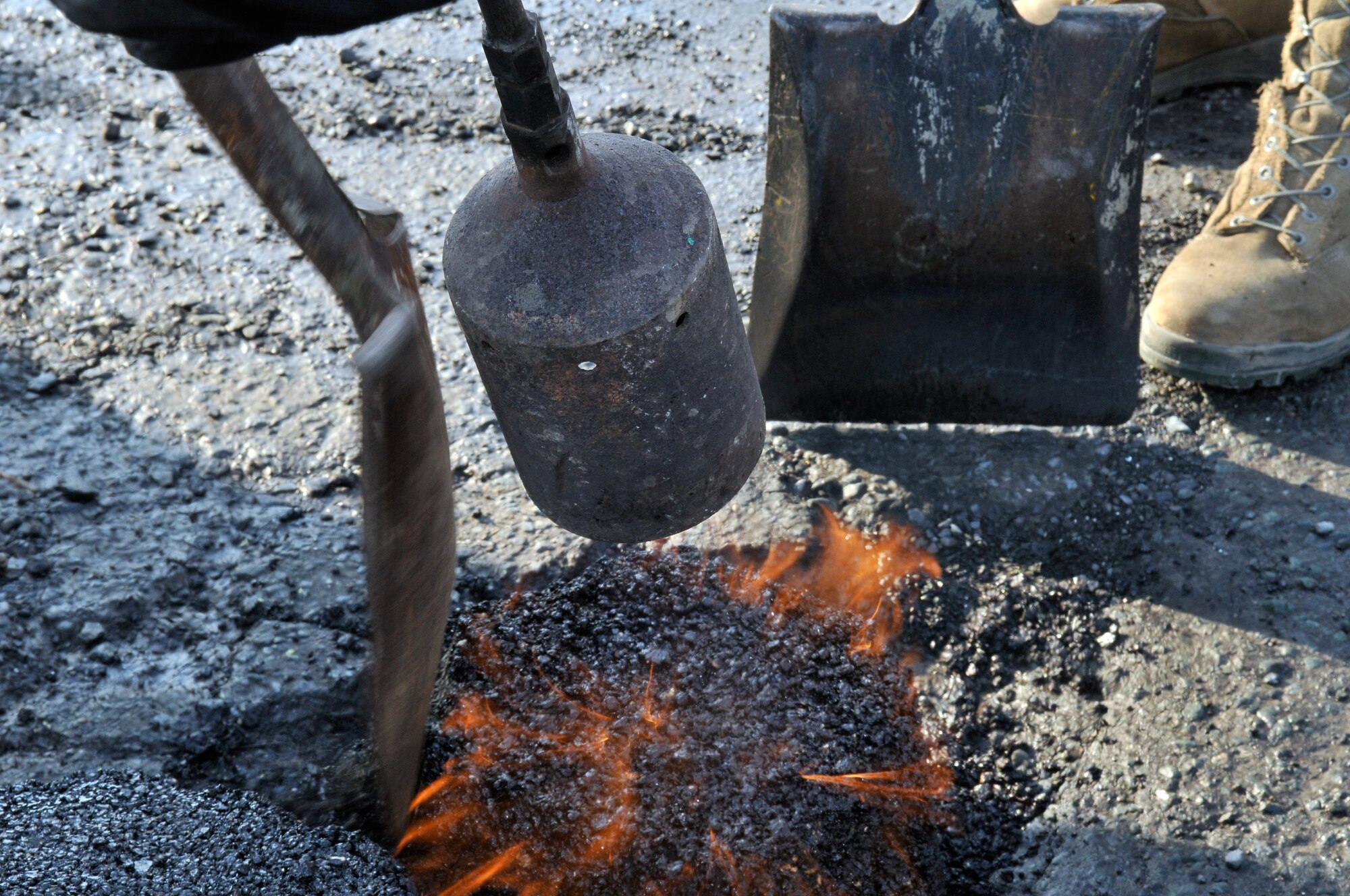 U.S. Air Force Airmen from the 35th Civil Engineering Squadron use portable propane torches and shovels to form an instant road repair compound into potholes March 29, 2012 at Misawa Air Base, Japan.  Potholes are typically caused by water that seeps into cracks and then freezes, causing the pavement to break and lift. (U.S. Air Force photo by Tech. Sgt. Phillip Butterfield/Released)