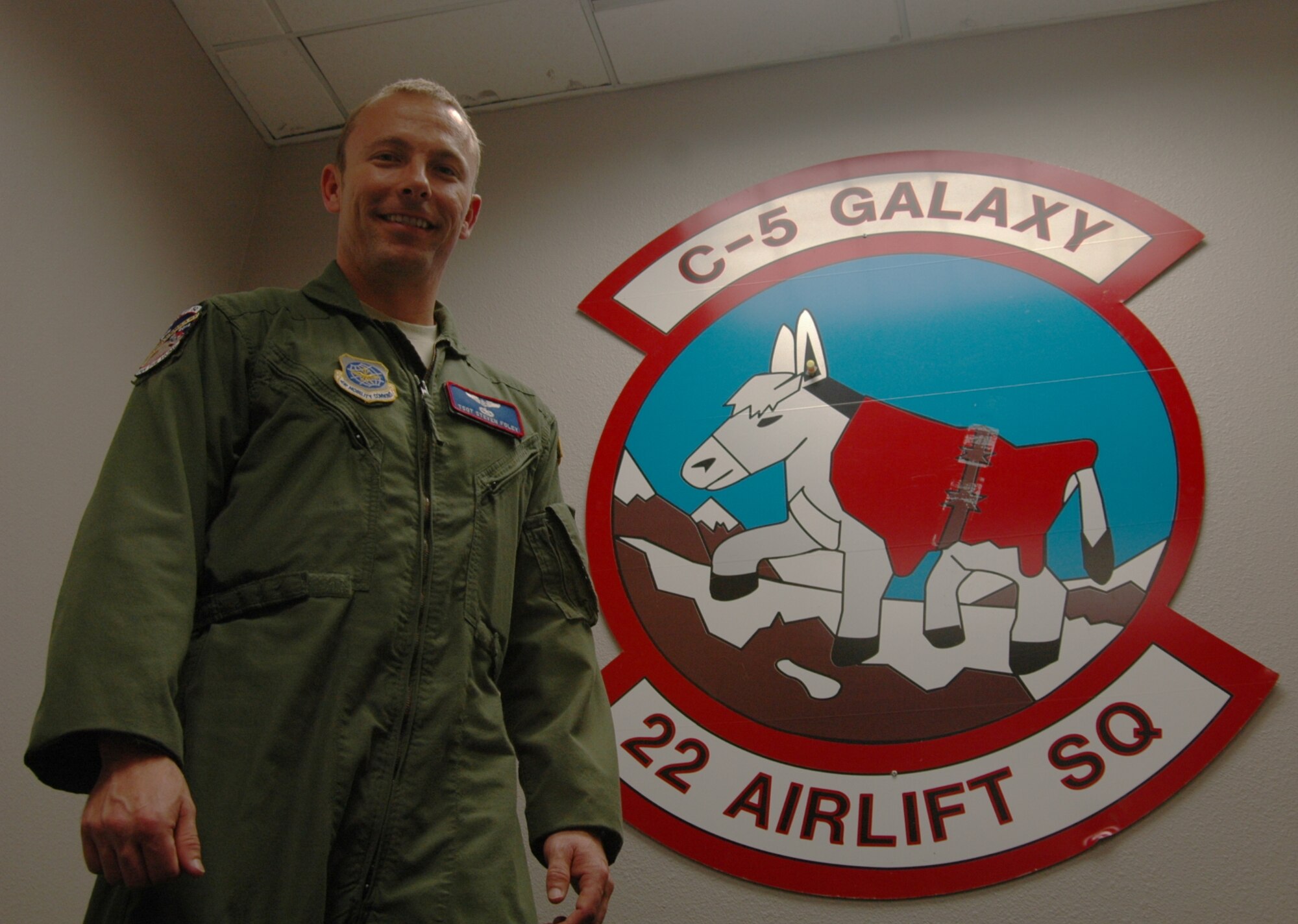 Tech. Sgt. Steven Foley, 22nd Airlift Squadron flight enginer, poses March 23 next to the squadron patch. (U.S. Air Force photo/ Nick DeCicco)